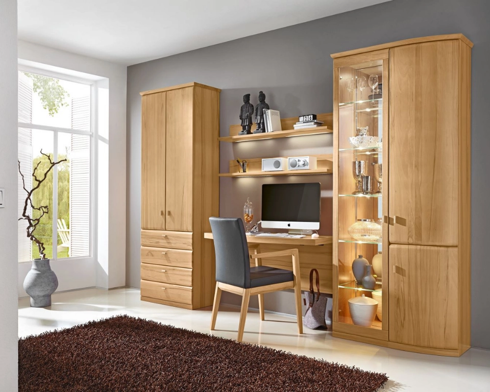 Funktionaler Arbeitsplatz mit natürlichem Licht und stilvollem Holzdesign. Heller Arbeitsbereich mit Holzschreibtisch, Vitrine, Regalen und Stuhl vor grauer Wand und großem Fenster.