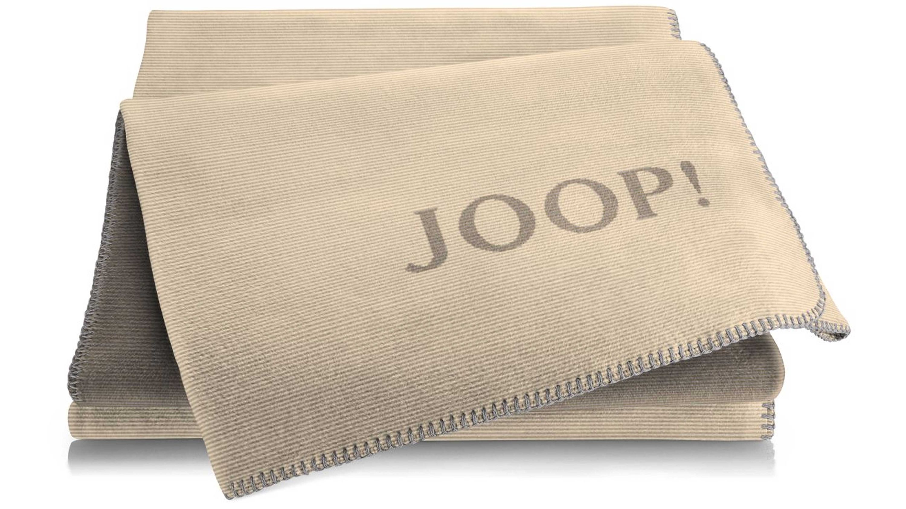 Beige Wohndecke mit grauem Rand und Schriftzug auf einer Seite gefaltet