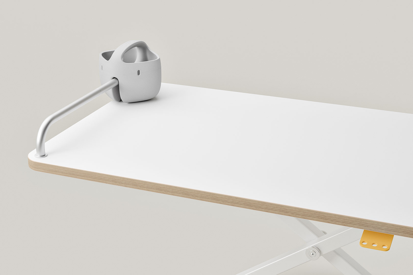 Gebogene Aluminium-Stange in Metallhalterung, befestigt an der Kante eines weißen Tisches.