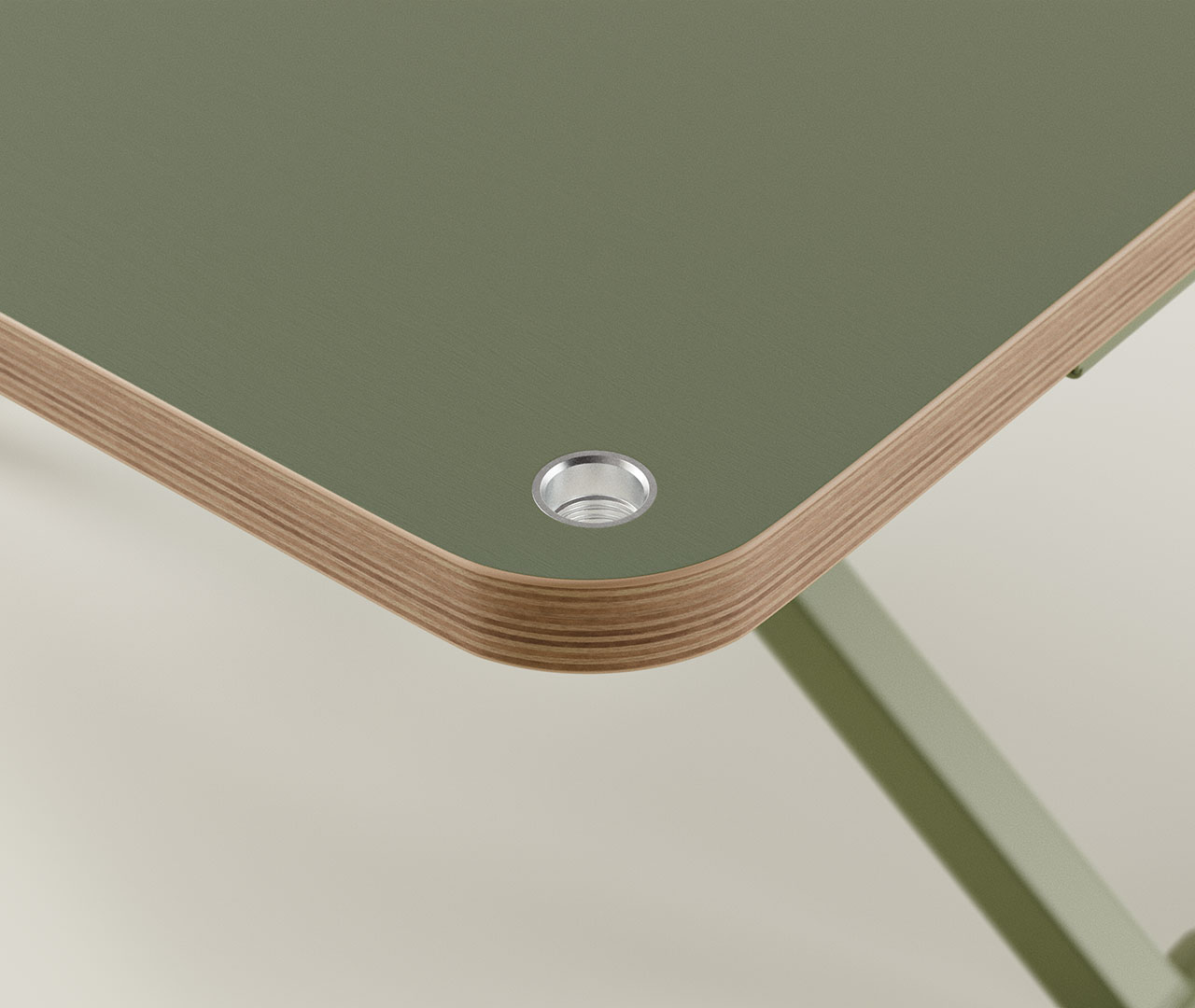 Detailansicht der popsnap-Verbindung am grünen Schreibtisch mit rundem Metallelement an der Tischkante.