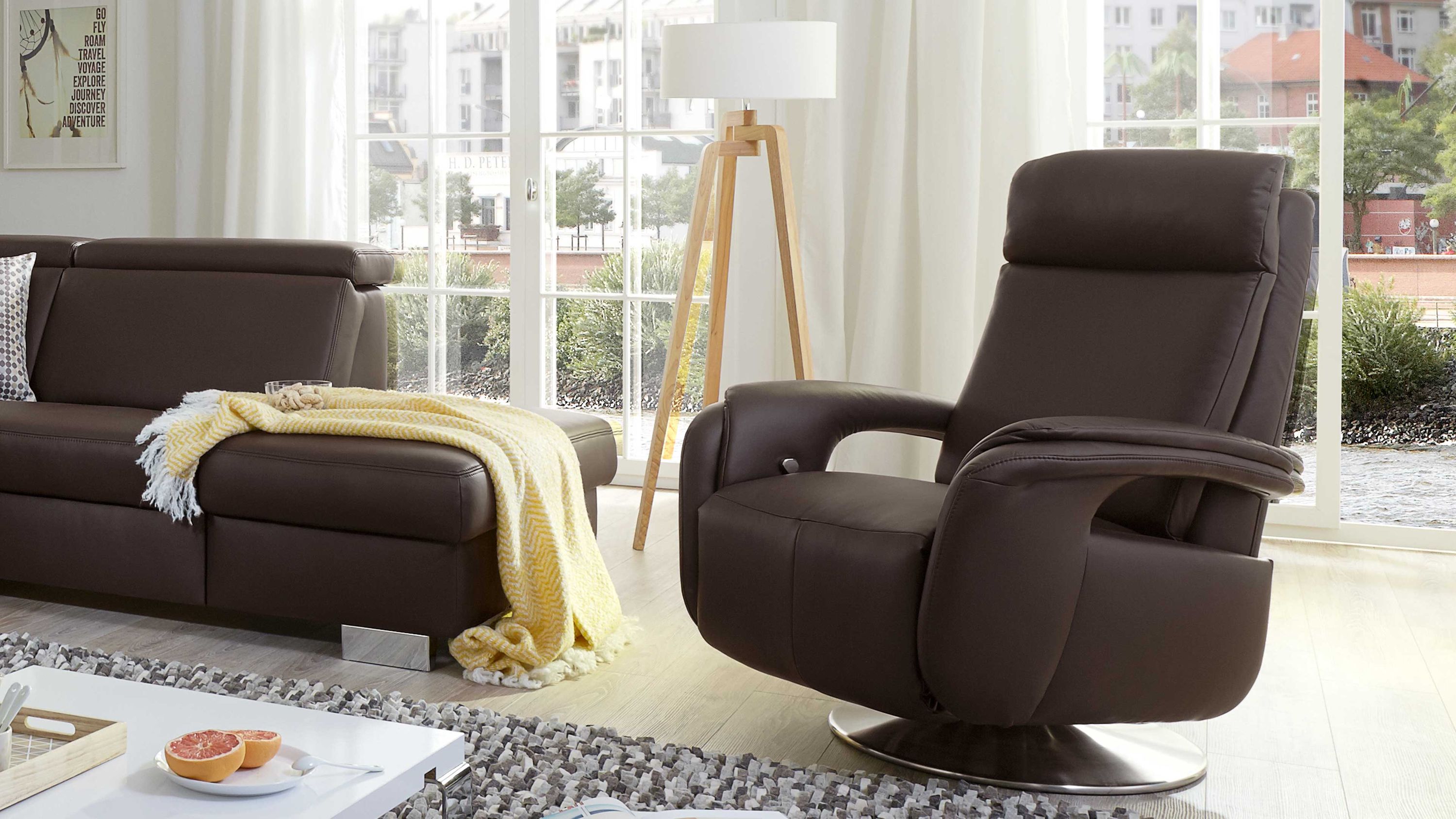Relaxsessel mit schokoladenbraunem Lederbezug und rundem Metallfuß in hellem Wohnzimmer