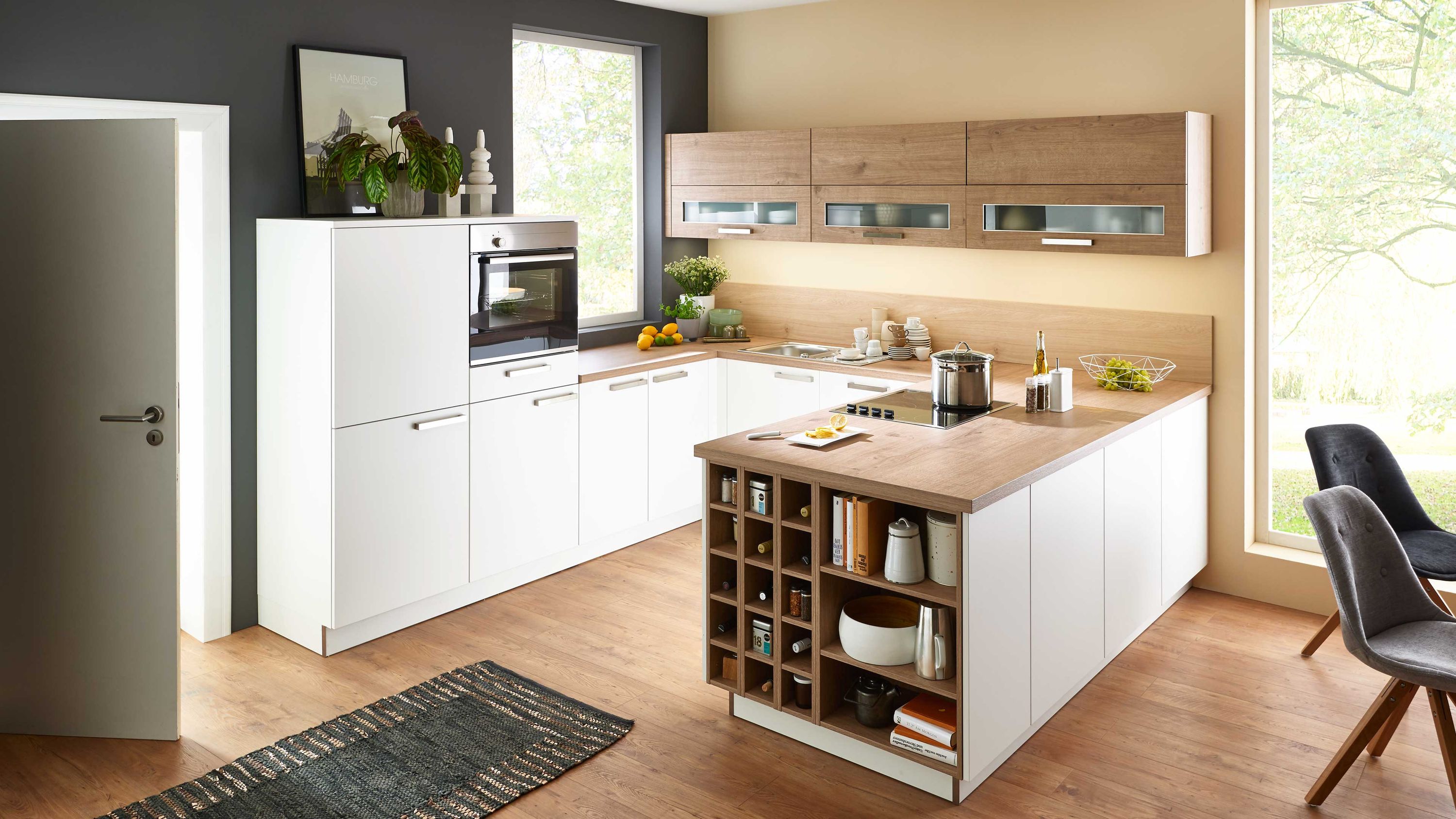 Helle Küche mit Insel Holzarbeitsplatte und Essbereich Weiße Fronten Holzplatte Kücheninsel mit Regal Einbaugeräte Fensterlicht Tisch mit zwei Stühlen