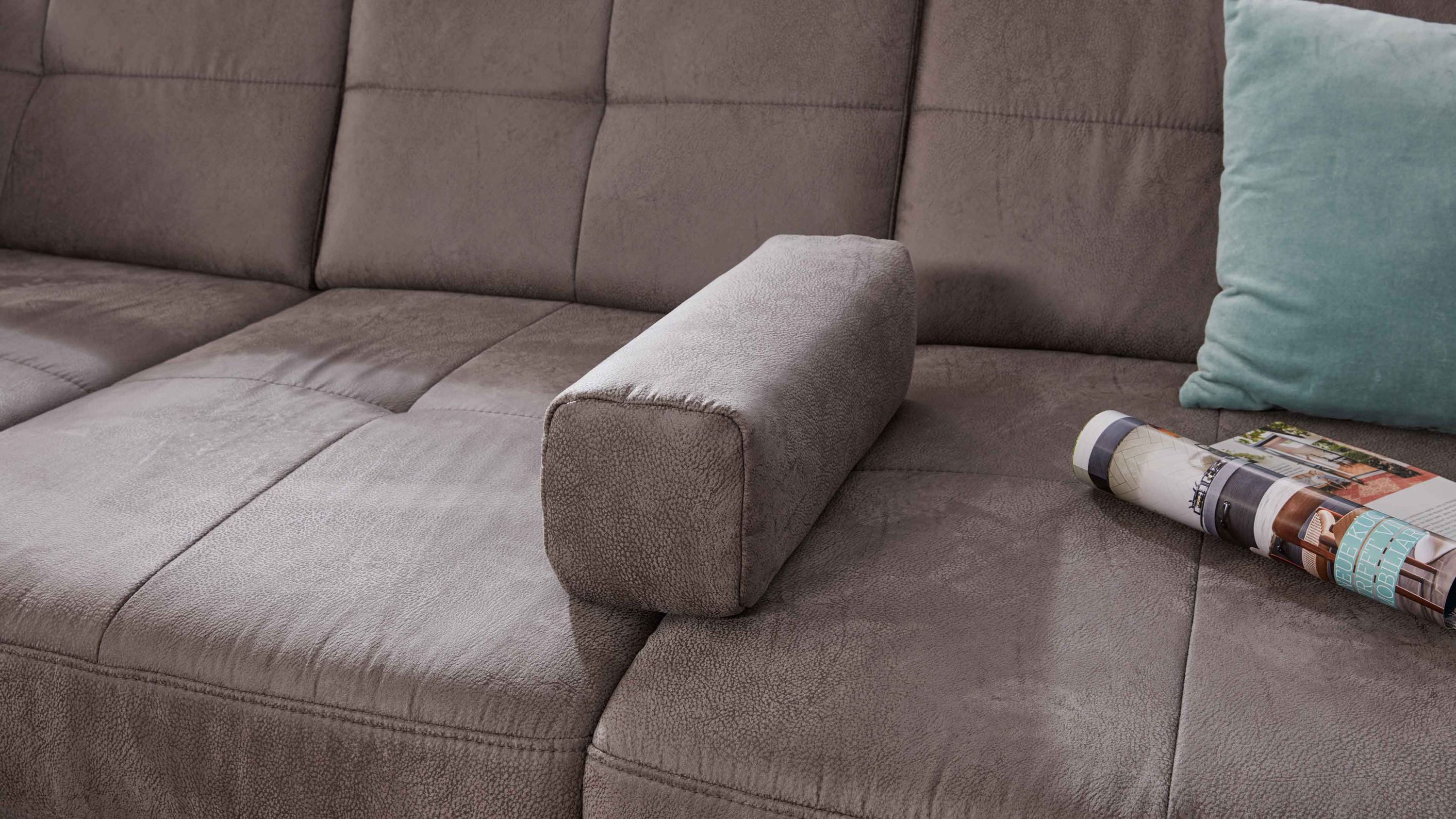 Rechteckiges graues Armlehnkissen aus Mikrofaser auf braunem Sofa mit Steppnähten