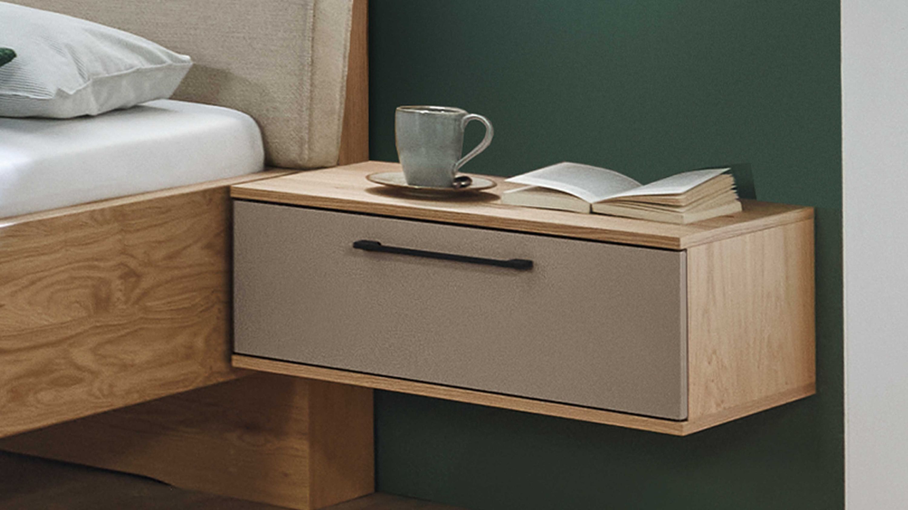 Hängende Konsole mit einer Schublade in taupe und Holzoptik an grüner Wand neben Bett