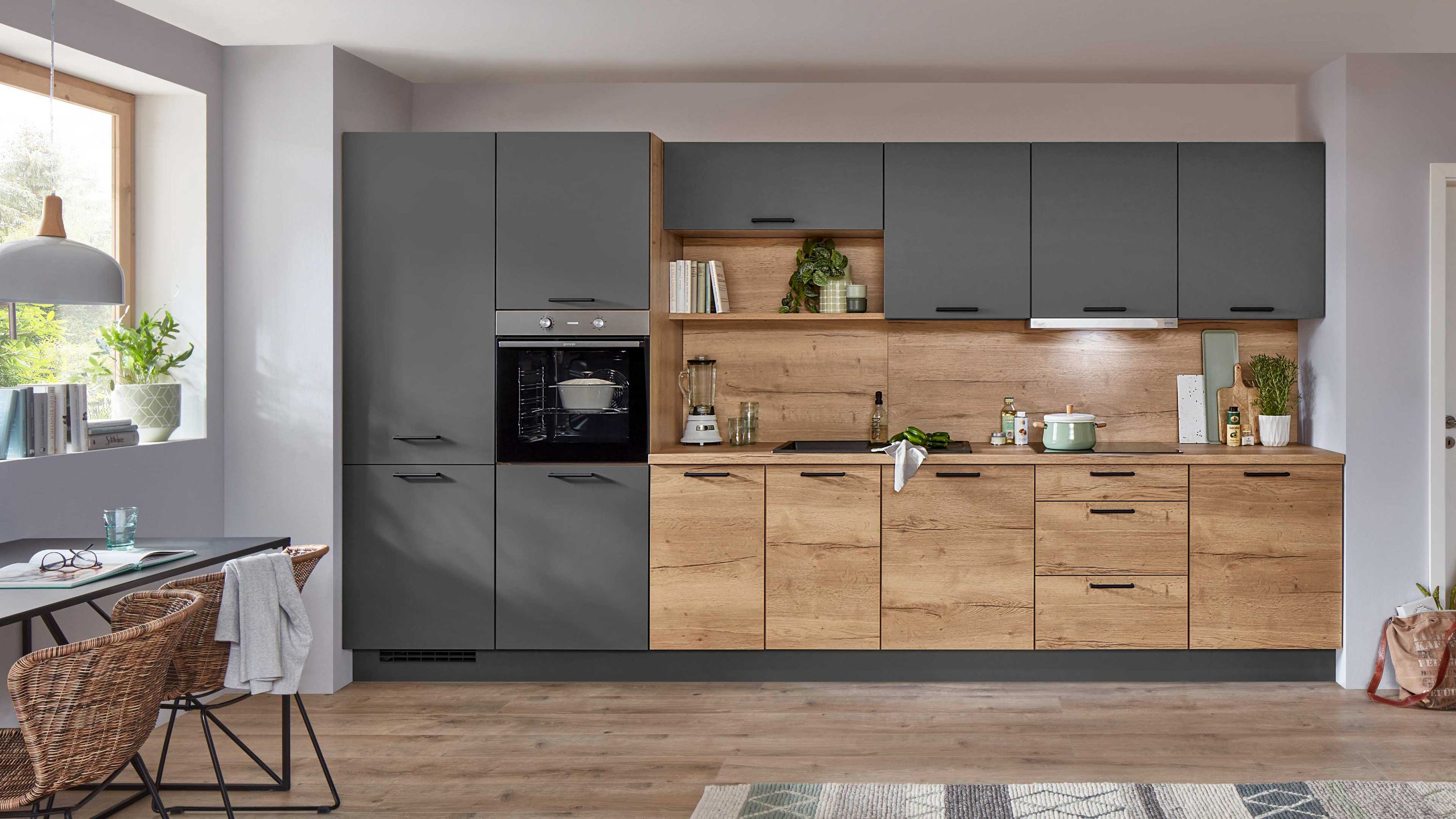 Küchenzeile in Holzoptik mit grauen Fronten offenen Regalfächern Einbauofen und moderner Beleuchtung.