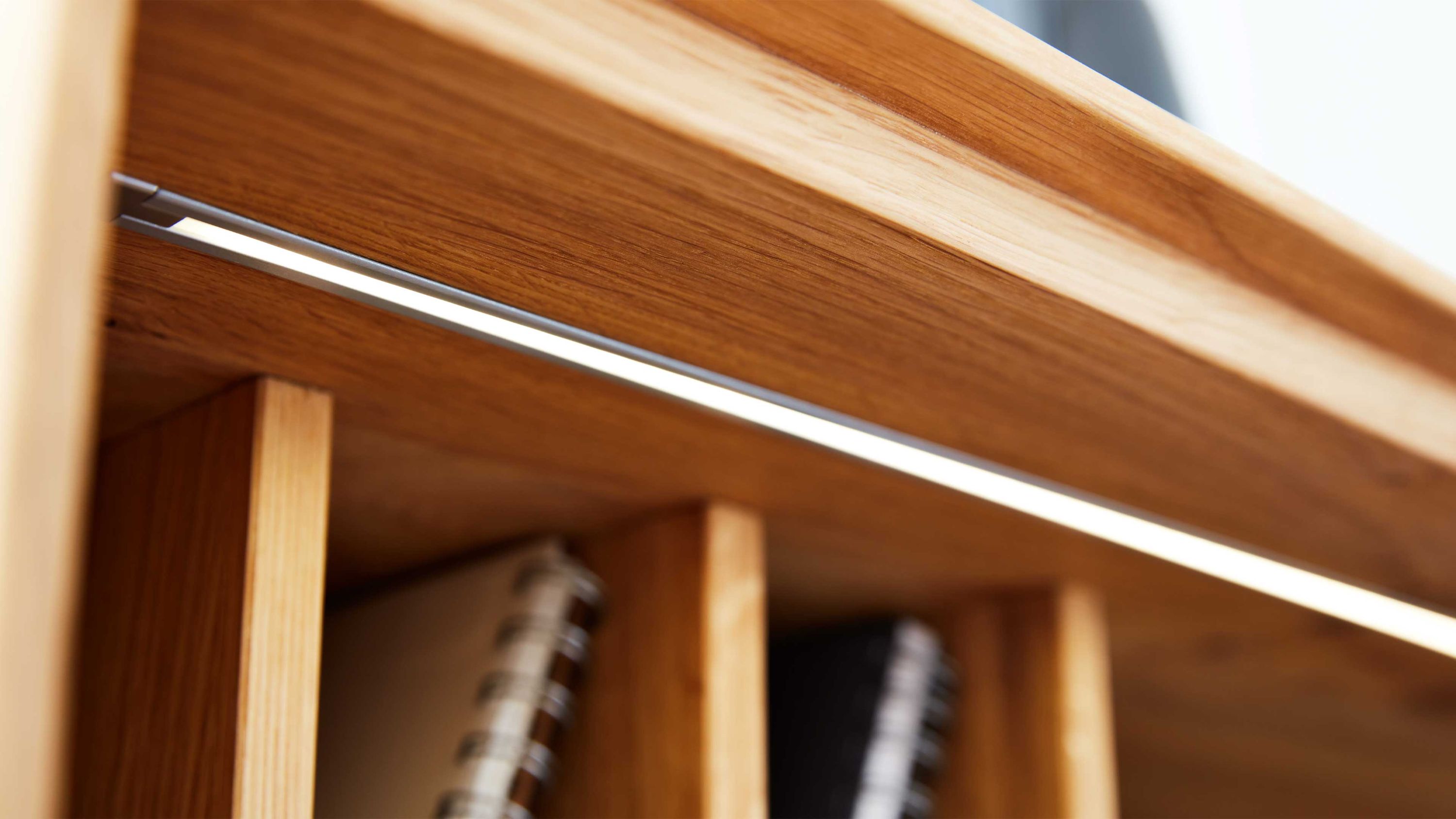 Innenbeleuchtung in einem Holzregal mit mehreren Fächern und Büchern