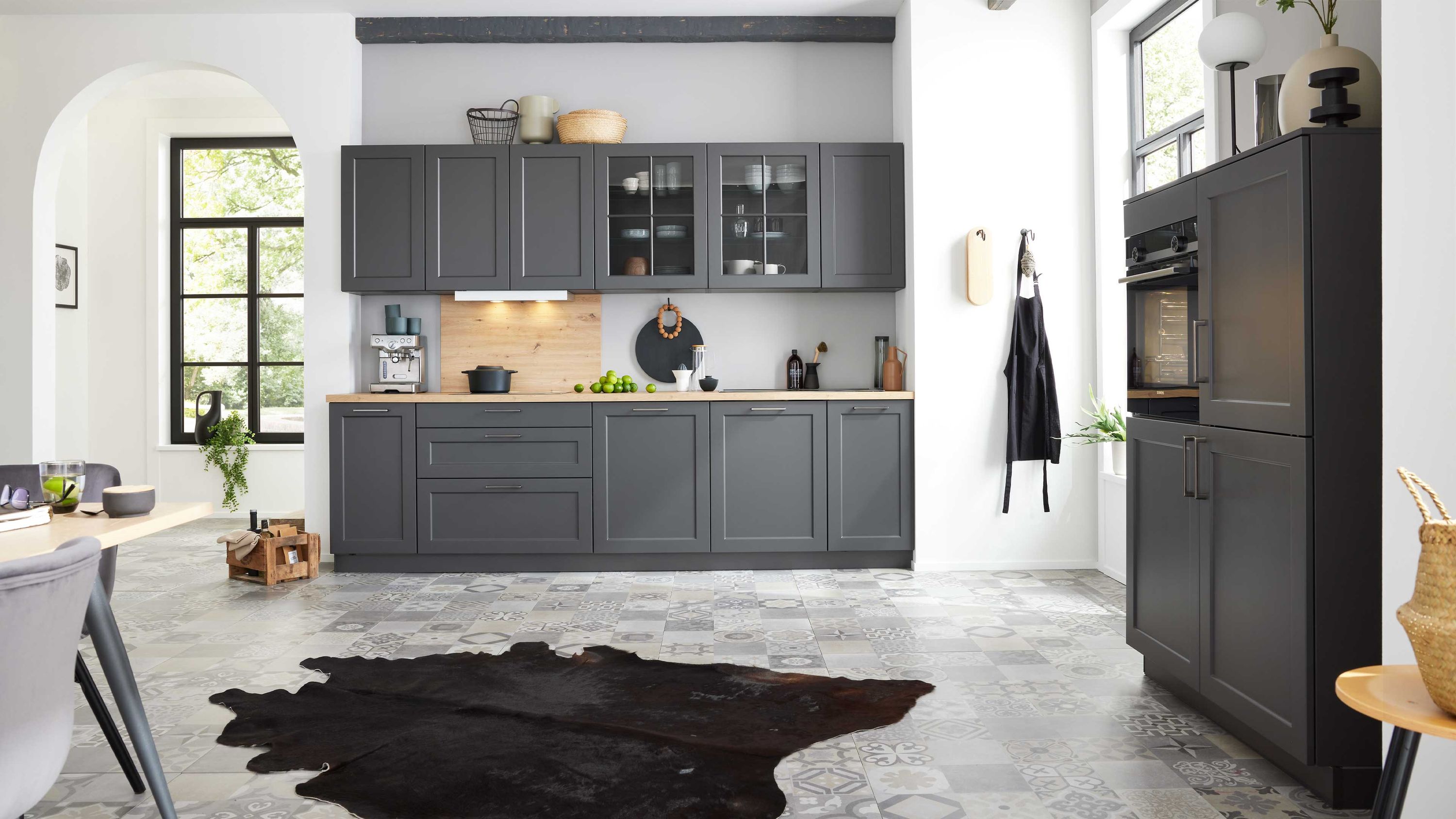 Küche mit dunklen Schränken großem Fenster schwarzem Teppich Geräten minimalistischem Dekor