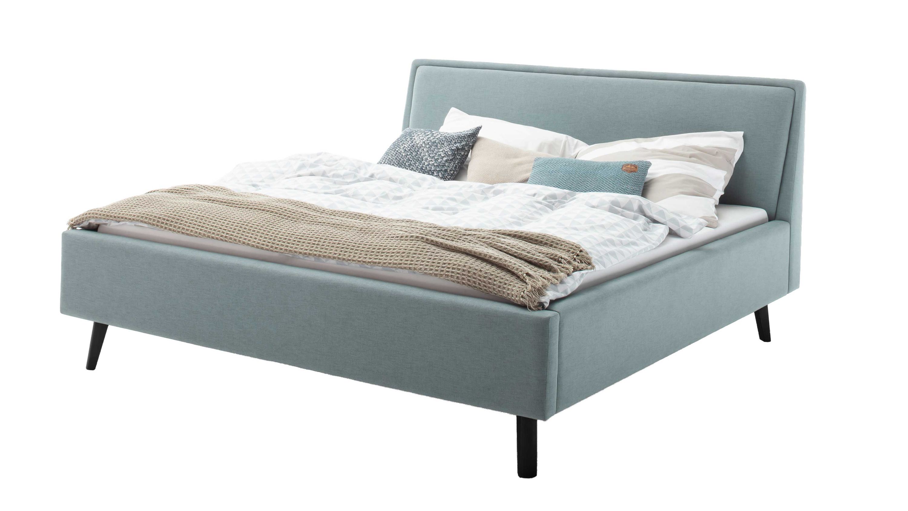 Polsterbettgestell mit eisblauem Bezug und Bettkasten Polsterbettgestell mit eisblauem Bezug schwarzer Holzfüße und Bettkasten mit Kissen und Decke belegt
