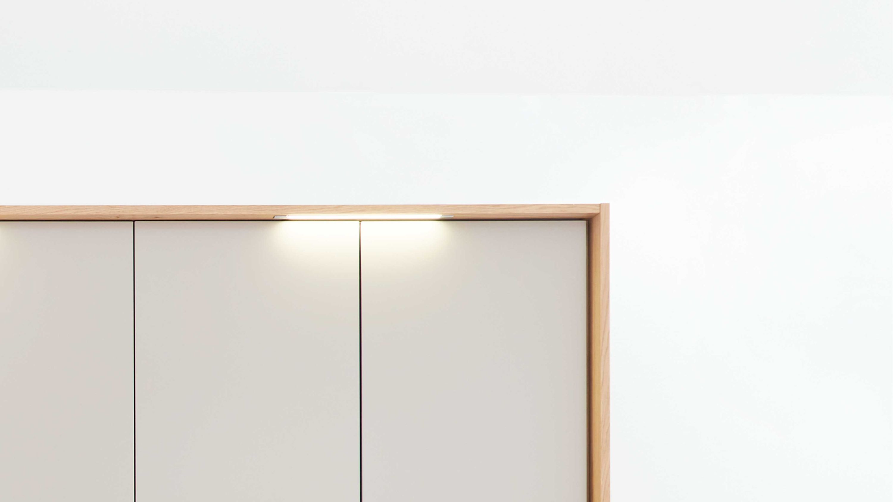 Schmale Stabbeleuchtung in weiß über einem hellen Schrank mit Holzrahmen