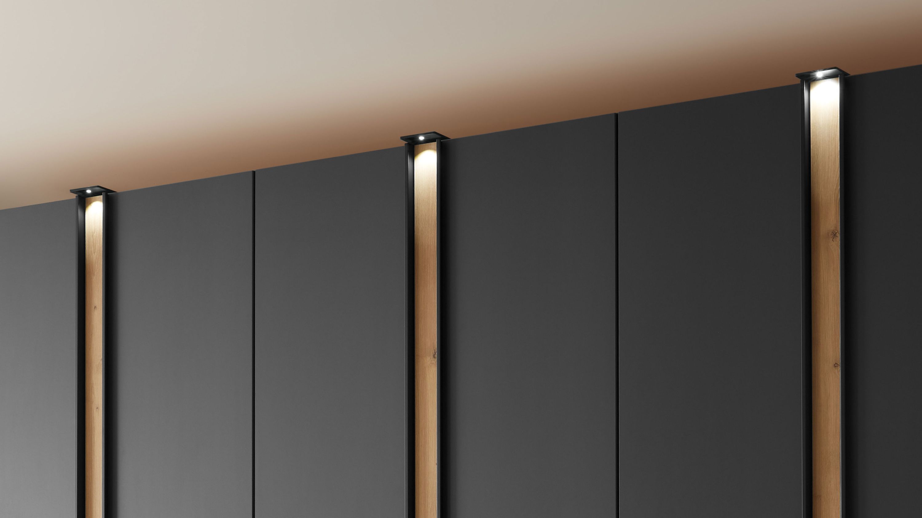 Dreiteiliger Kleiderschrank mit schwarzen Türen und vertikaler LED-Beleuchtung in Holzoptik
