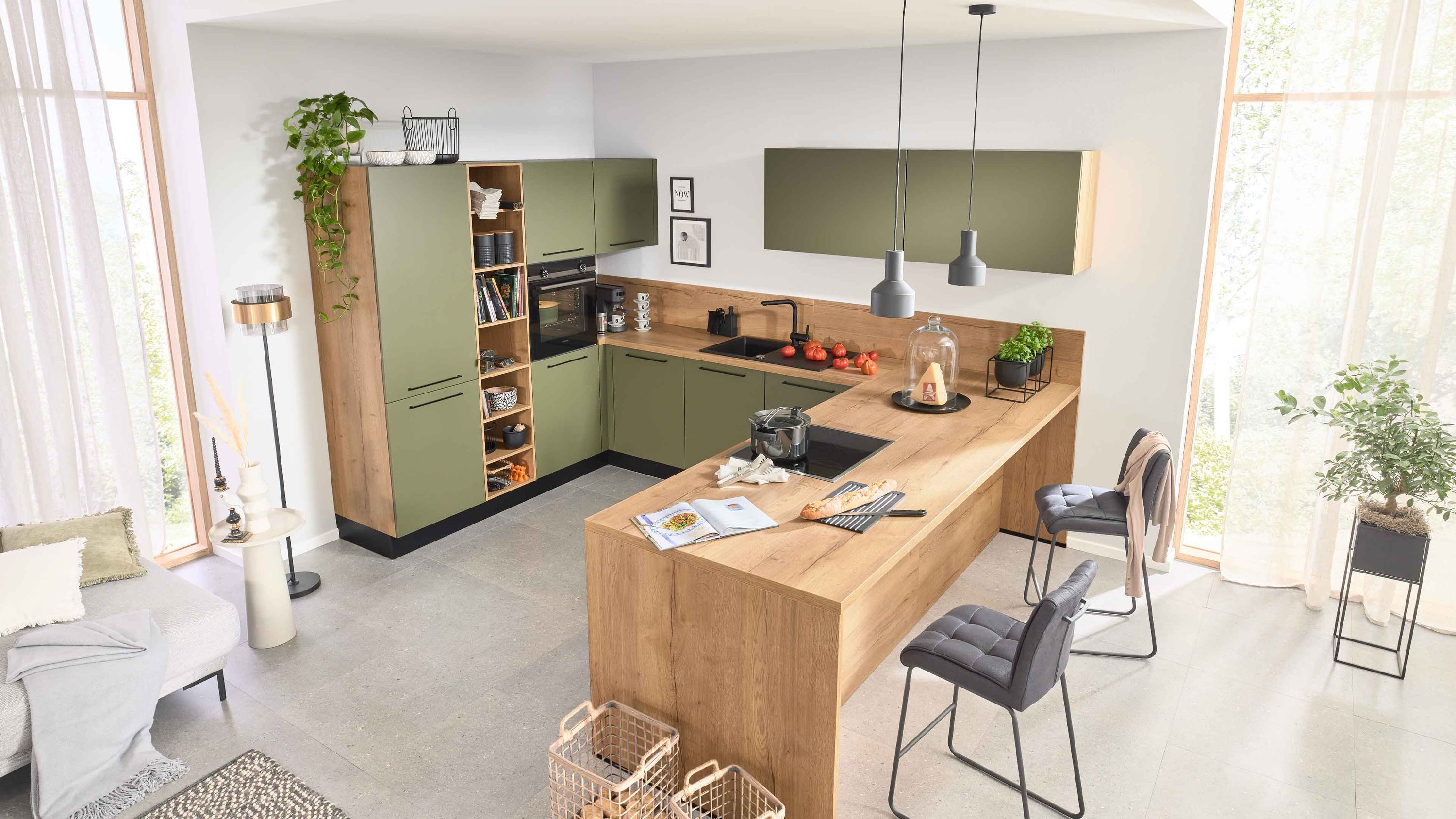 Moderne Designküche mit Tageslicht und Naturakzenten Moderne Küche mit grünen Fronten Holzarbeitsplatte Insel mit Spüle Barhockern Pflanzen und Tageslicht