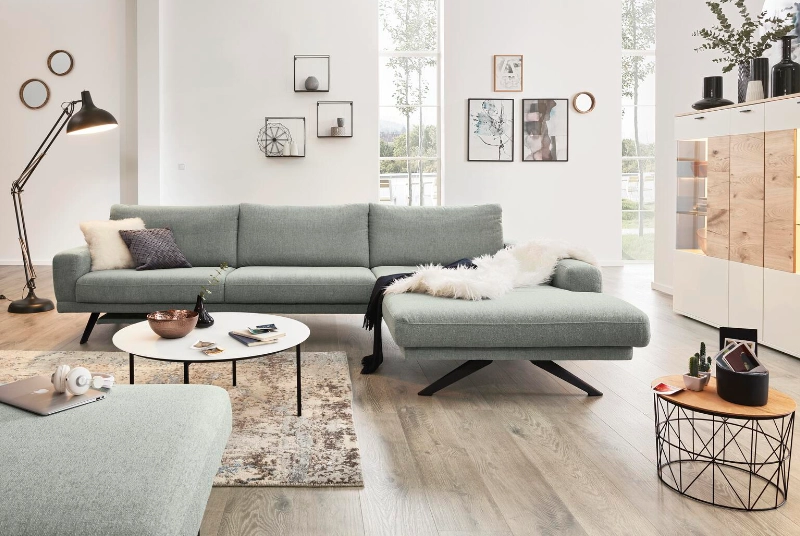 Stilvolles Ecksofa mit Holzfüßen und hellen Accessoires in modernem Raum