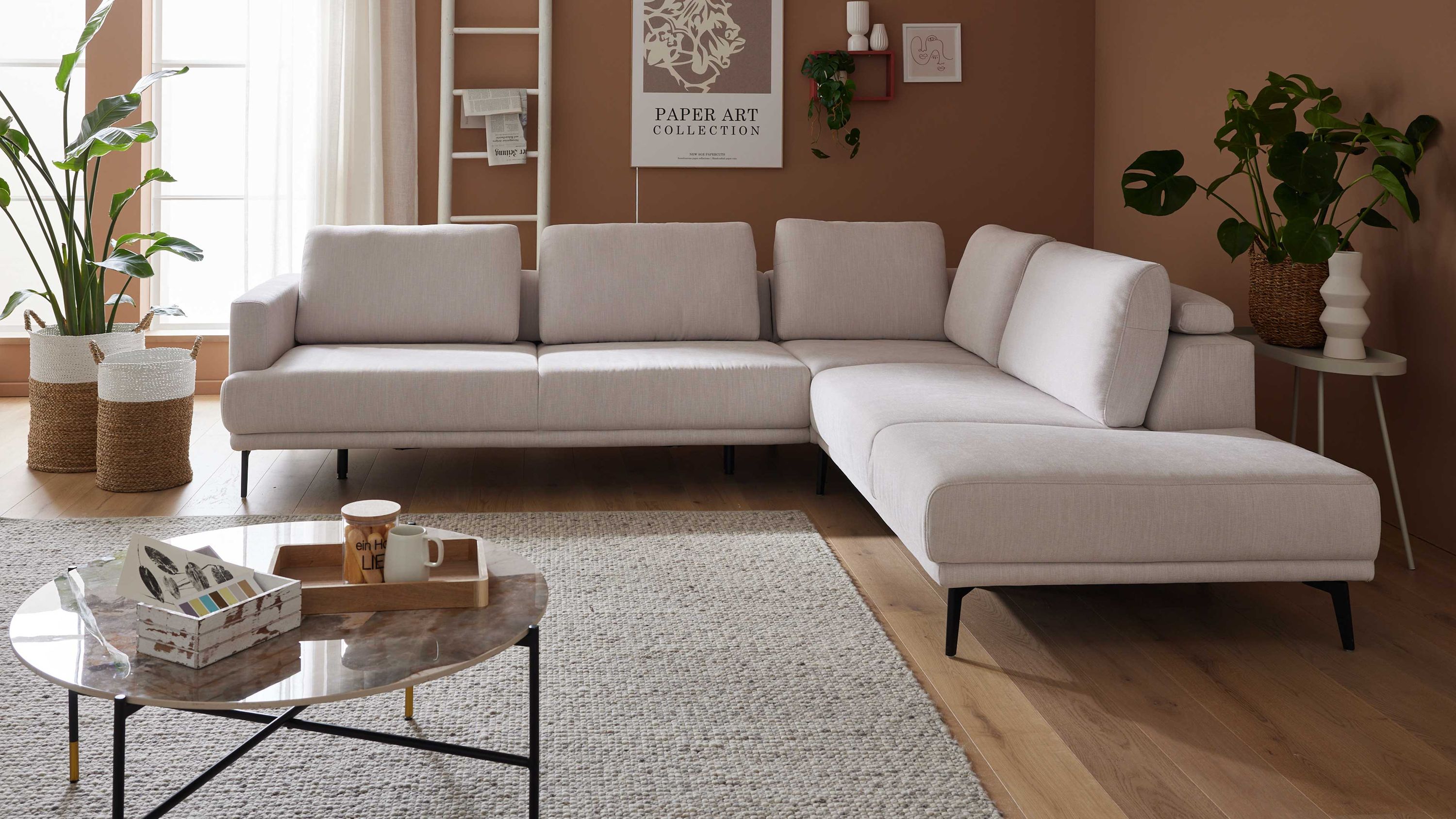 Ecksofa mit ecrufarbenem Stoffbezug und schwarzen Metallfüßen in modernem Wohnzimmer