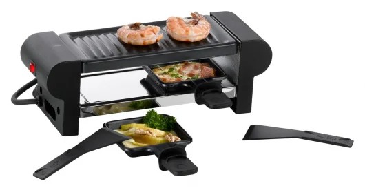 Kompaktes schwarzes Raclette-Gerät mit Grillplatte  zwei Pfännchen und Griffen auf heller Fläche
