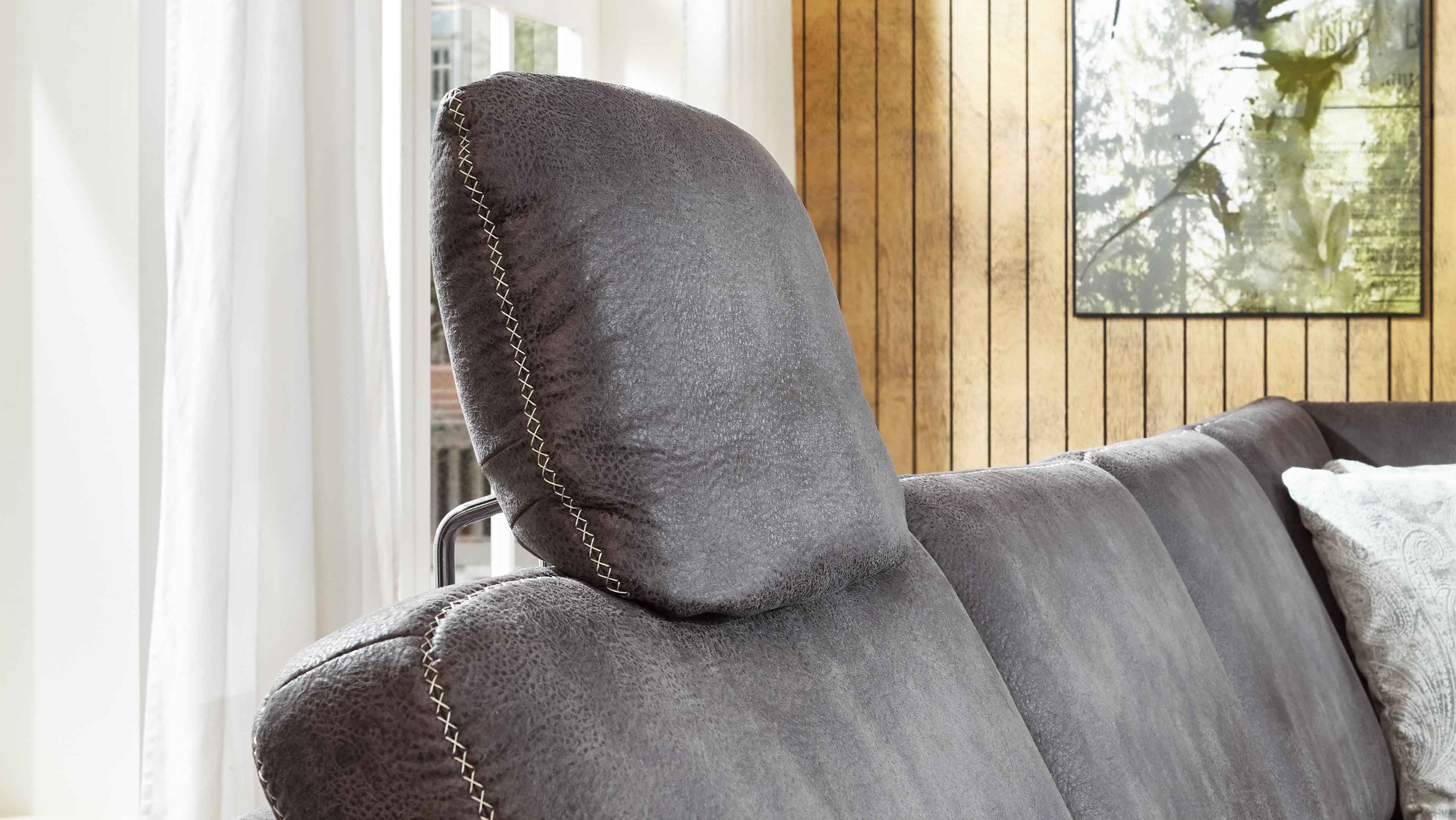 Graue Kopfstütze mit Stoffbezug und sichtbaren hellen Nähten auf einem Sofa