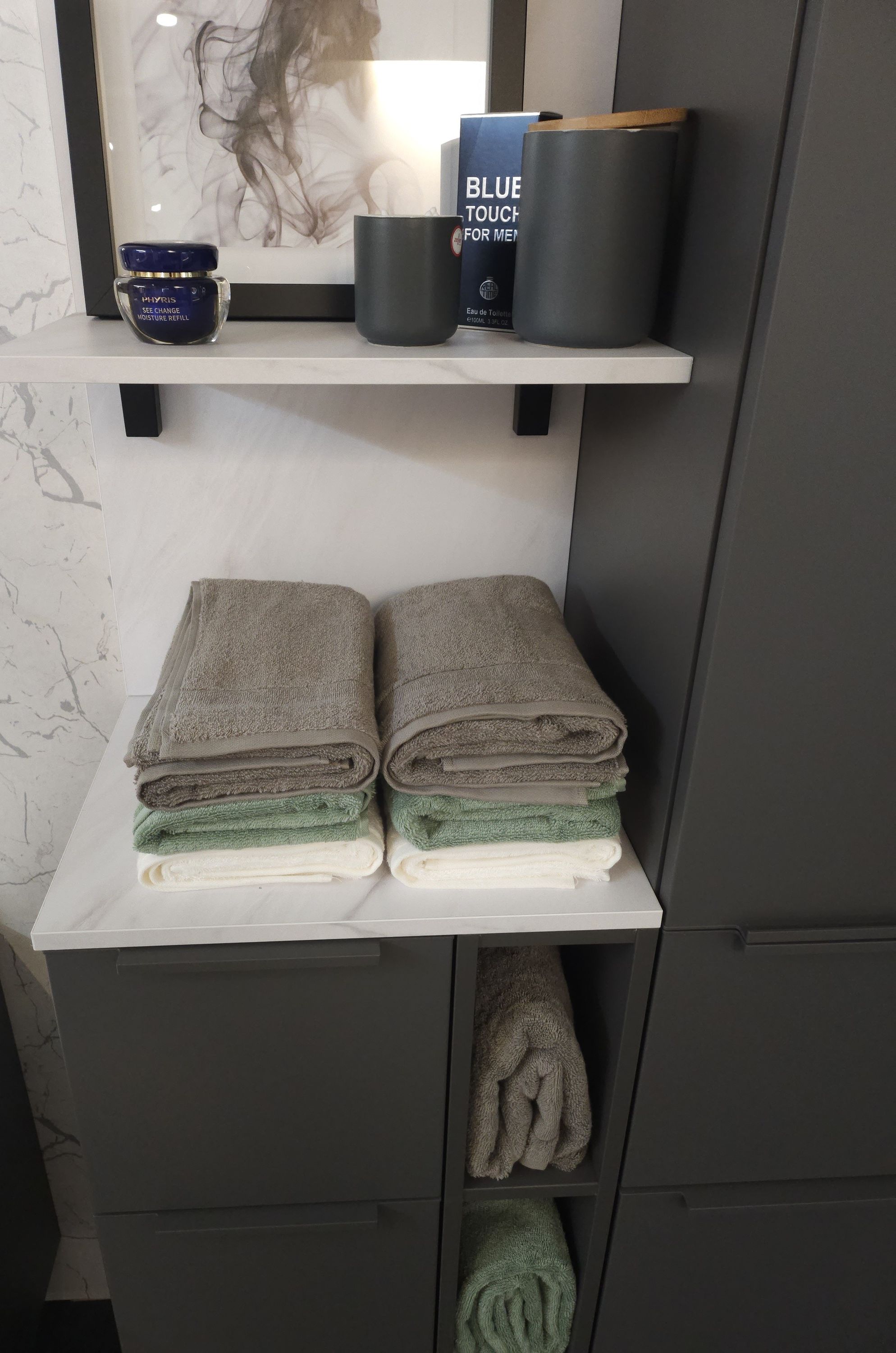 Badezimmerregal mit grauen Handtüchern Bild blauem Behälter und Dosen in Frontalansicht präsentiert