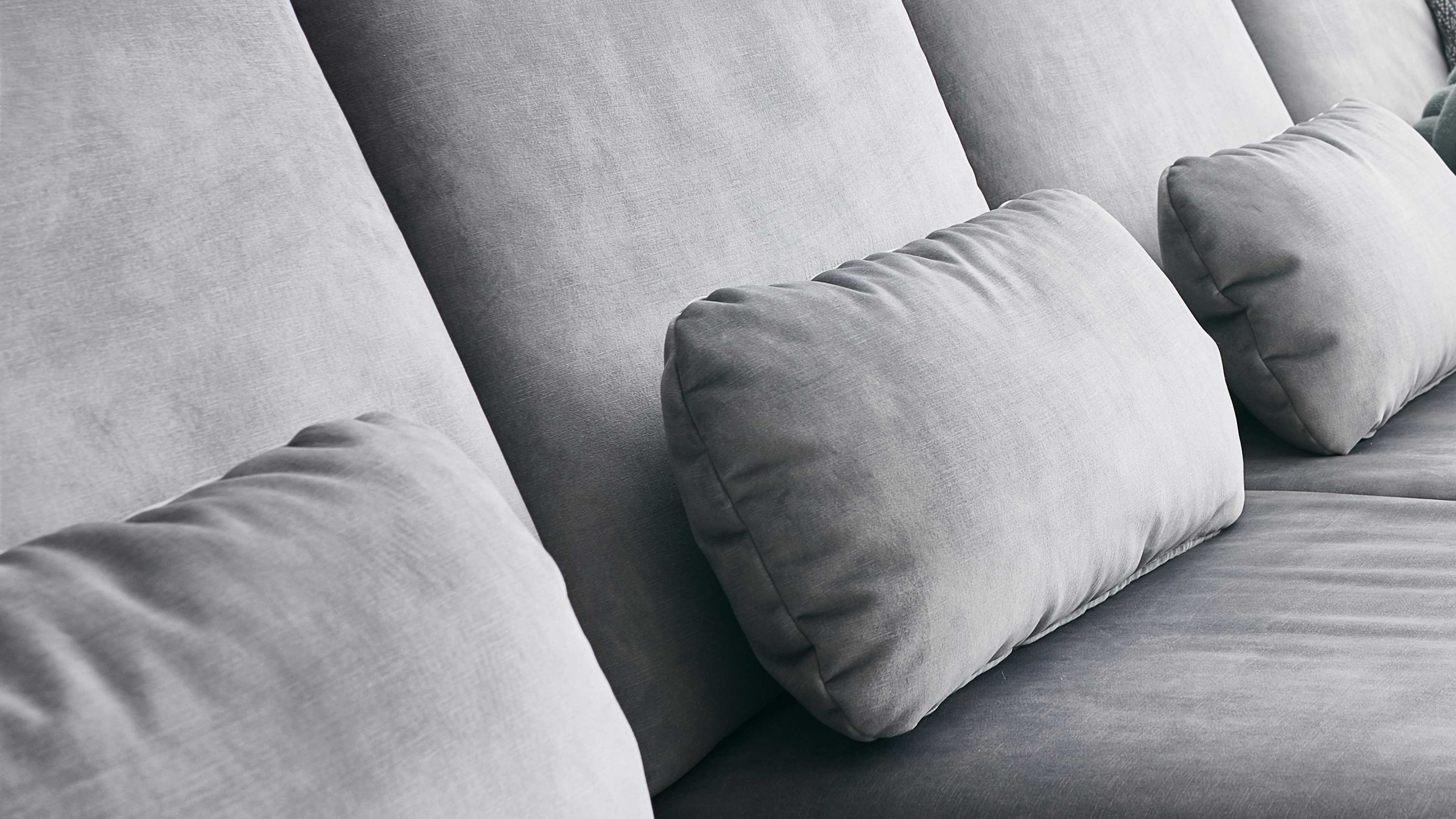 Silberfarbenes Nierenkissen aus Velours auf grauem Sofa