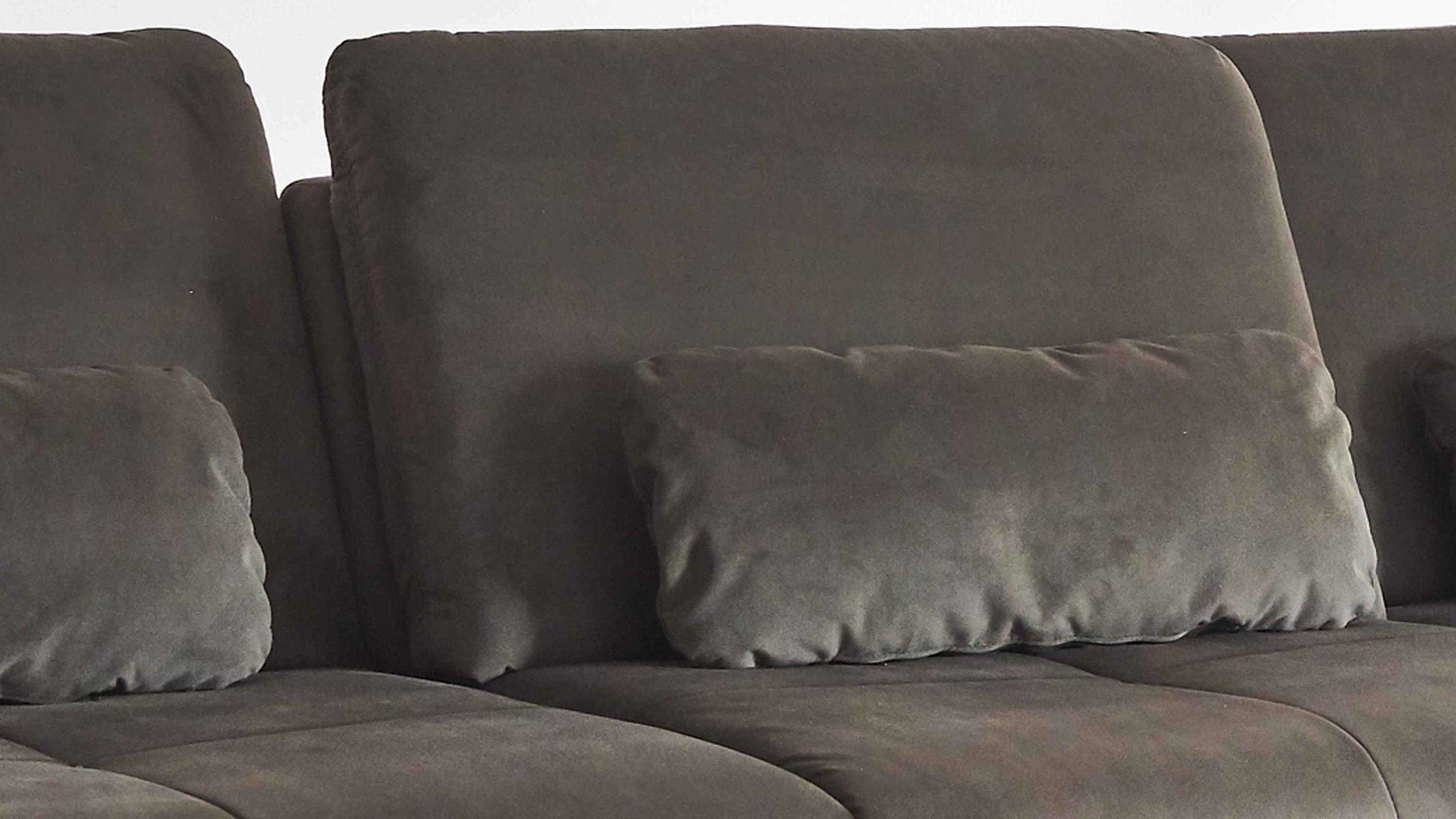 Dunkelgrünes Sofa mit mehreren rechteckigen Kissen in gleicher Farbe