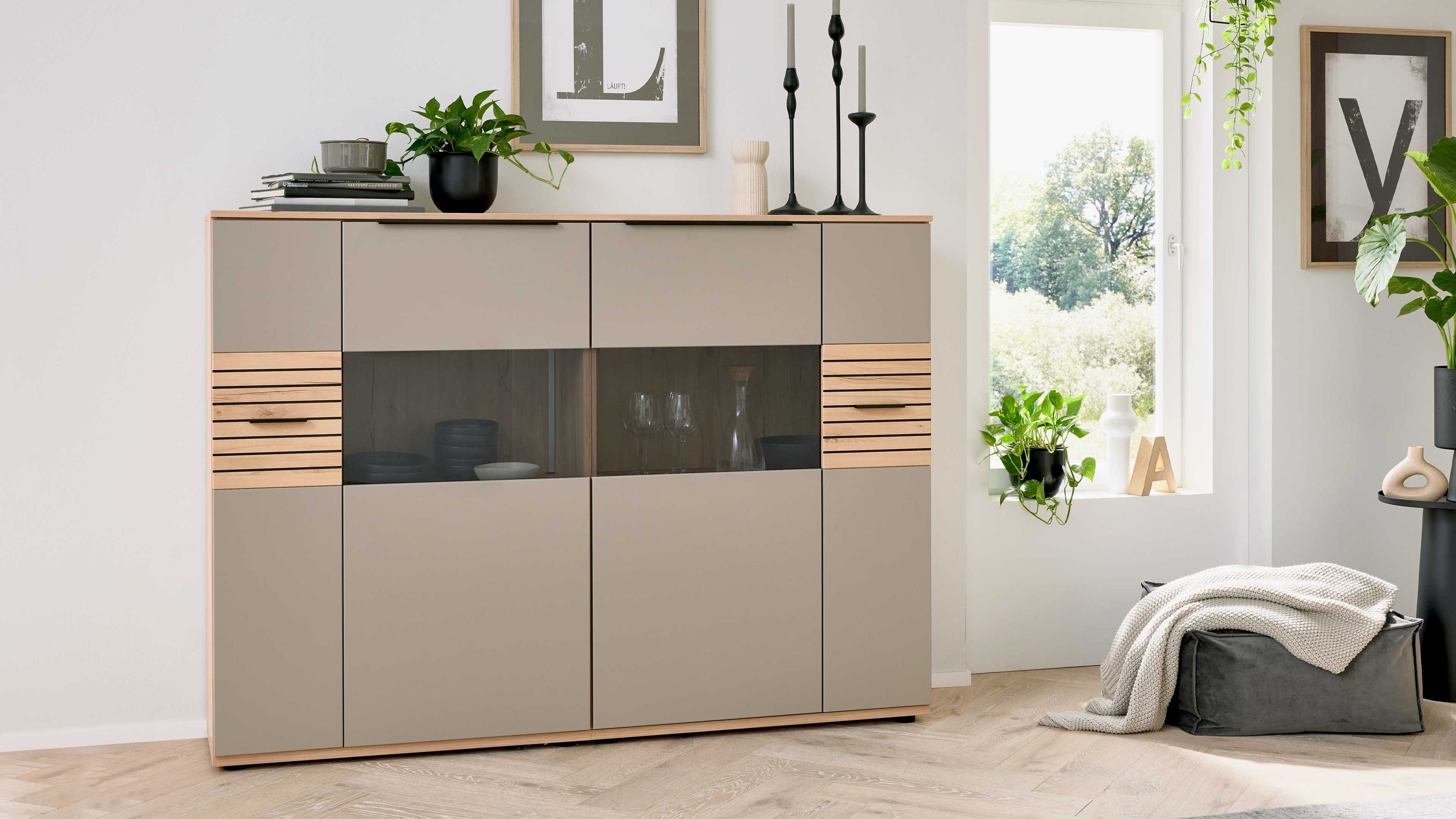 Helles Highboard mit vier Türen grauen Fronten und Holzdetails mittig mit Glasfenster