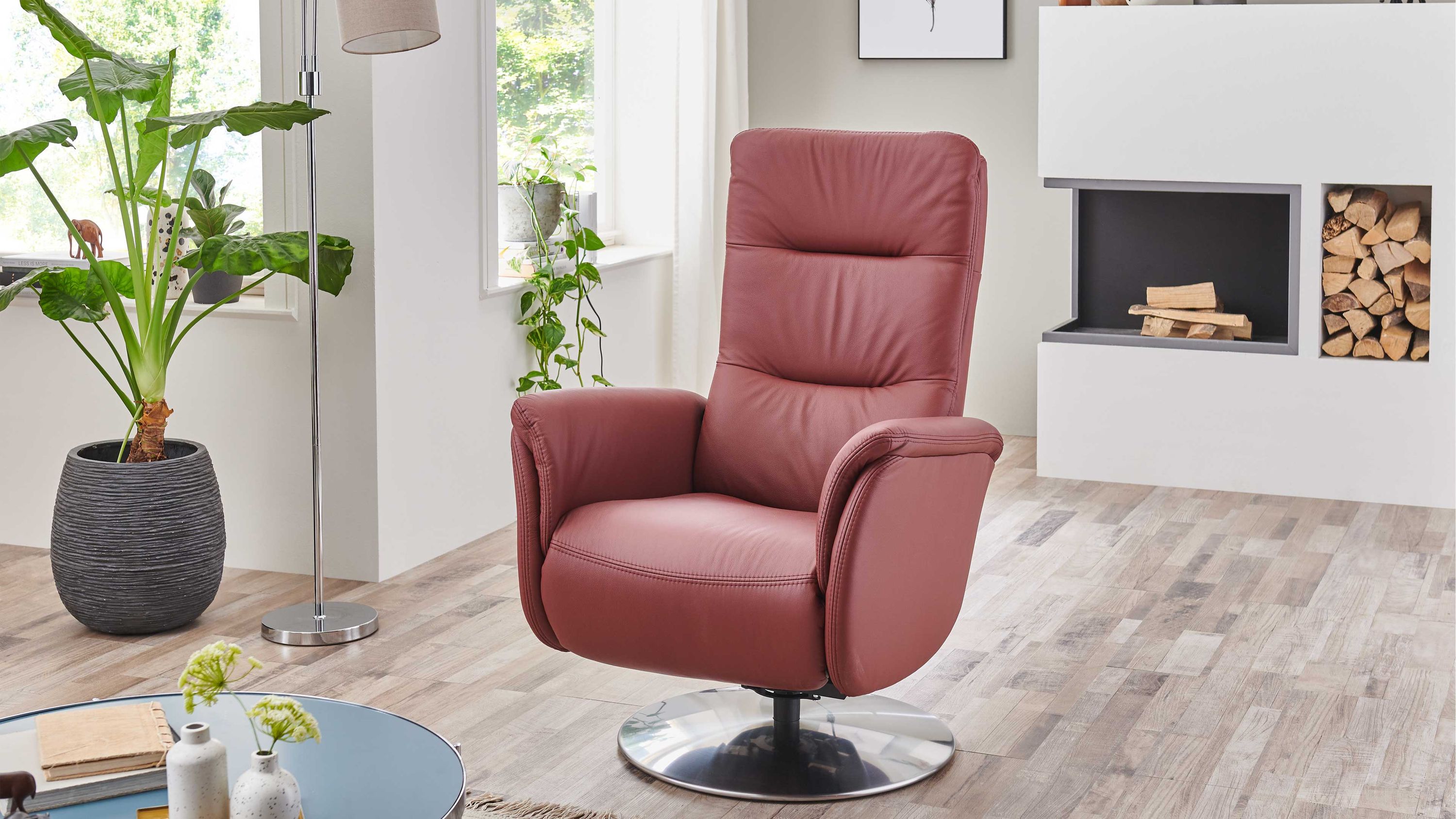 Relaxsessel mit rundem Metallfuß und brombeerfarbener Polsterung Relaxsessel mit hoher Rückenlehne und Armlehnen in brombeerfarbener Polsterung auf rundem Metallfuß