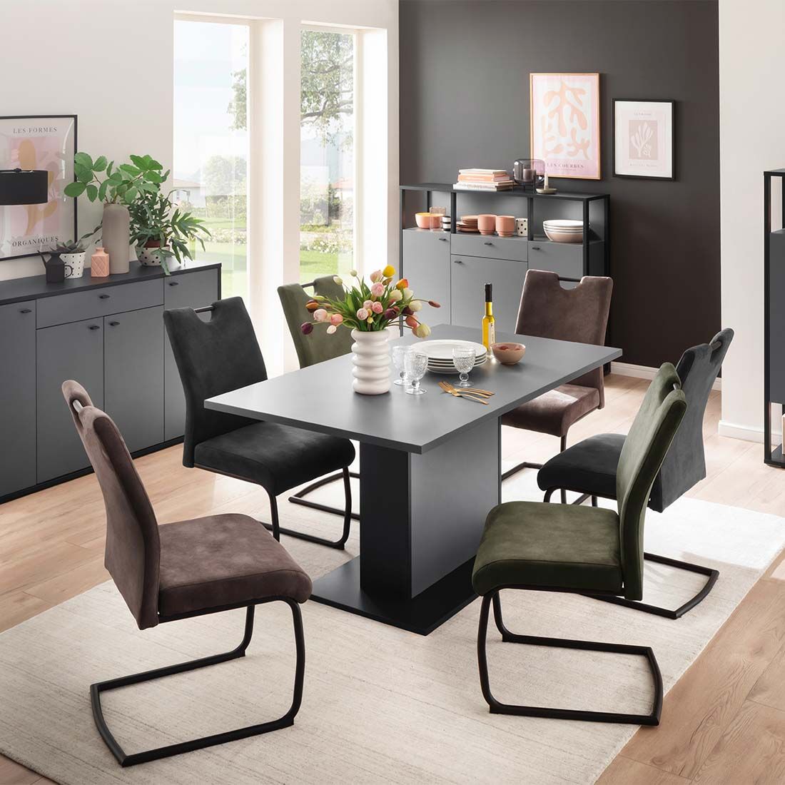 Esszimmer mit Tisch & 6 Polsterschwingstühlen (einer grün) Holzboden Fenstern & Deko frontal fotografiert