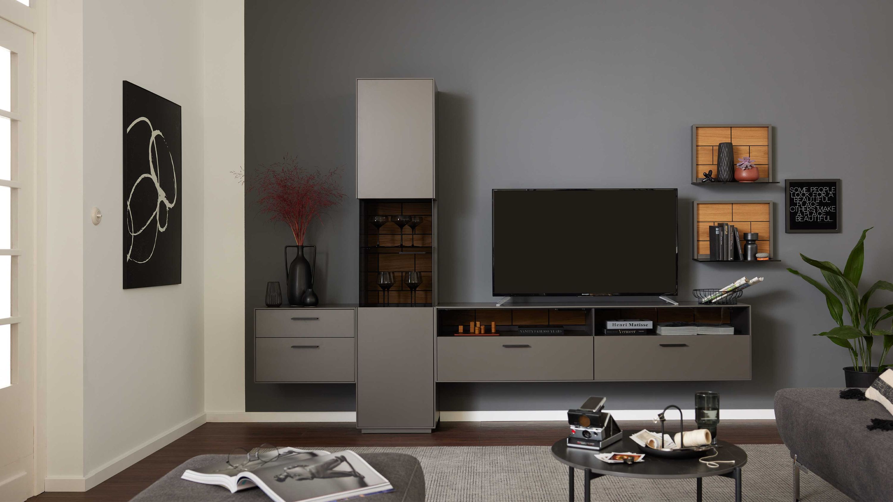 Fünfteilige graue Wohnwand mit Holzrückwänden Fünfteilige Wohnwand mit grauen Fronten und Holzrückwänden bestehend aus Schränken und Regalen an grauer Wand