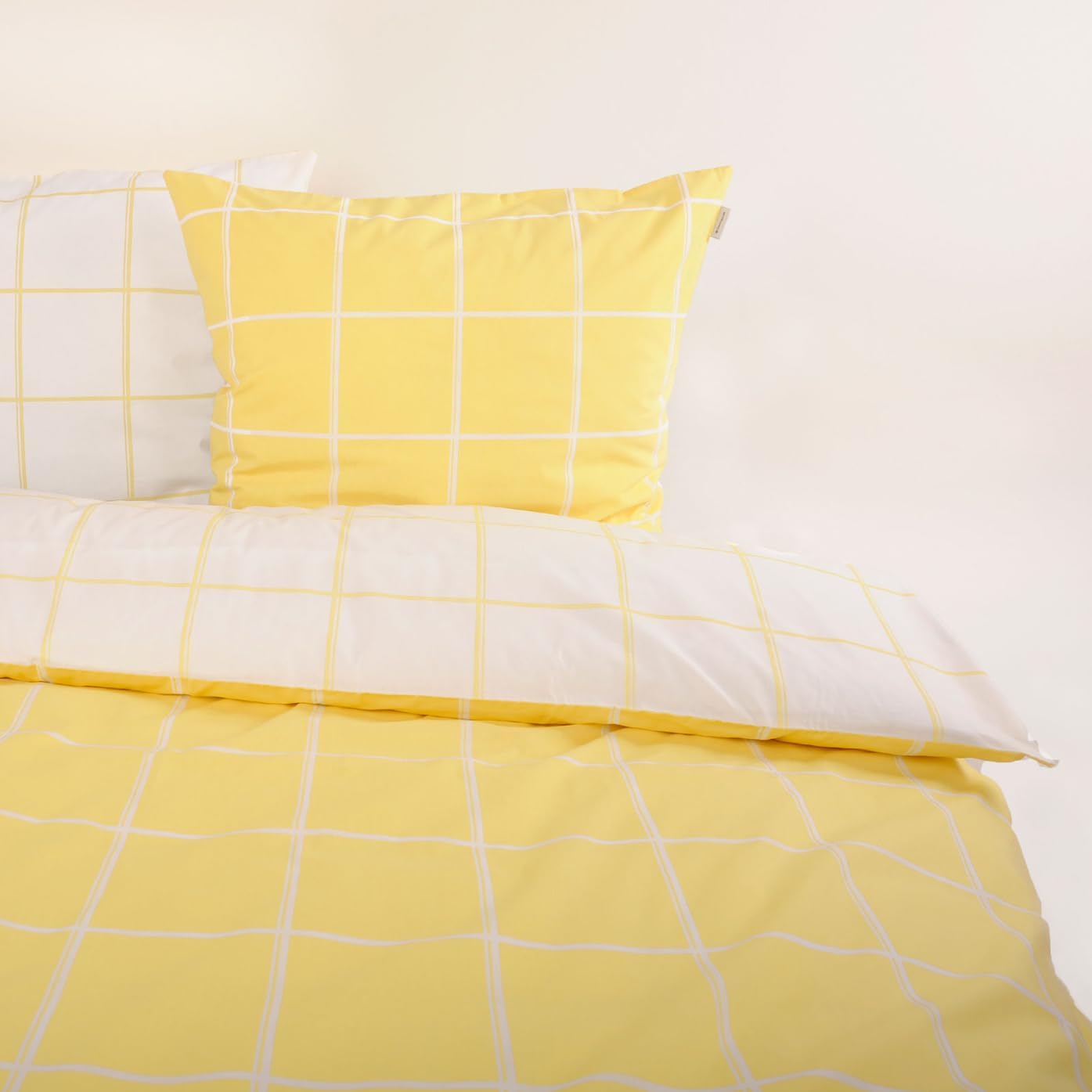 Gelb-weiß kariertes Bettwäsche-Set mit Kopfkissen und Bettdecke, von schräg oben fotografiert