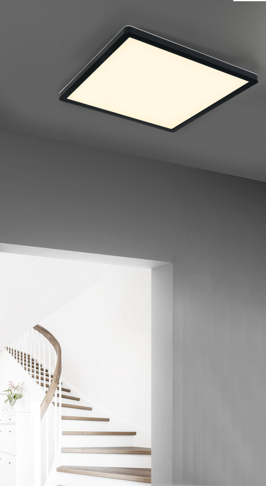 Rechteckige Deckenleuchte mit schwarzem Rahmen und weißer Lichtfläche Raum mit grauen Wänden und Treppe