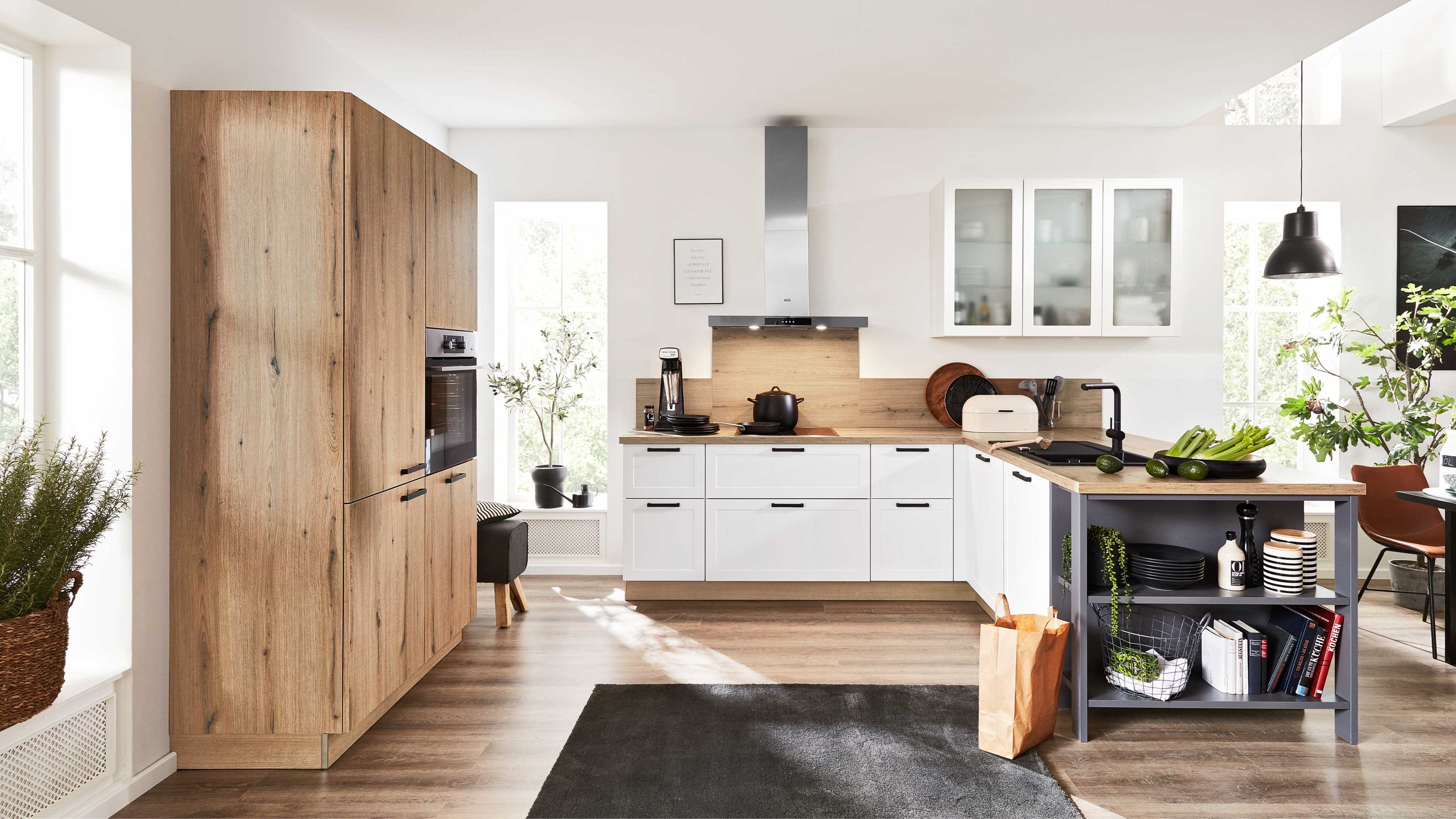 Küche mit weißen Fronten Holzschrank mit Einbauofen Holzfußboden hellem Arbeitsbereich und schwarzen Teppichdetails