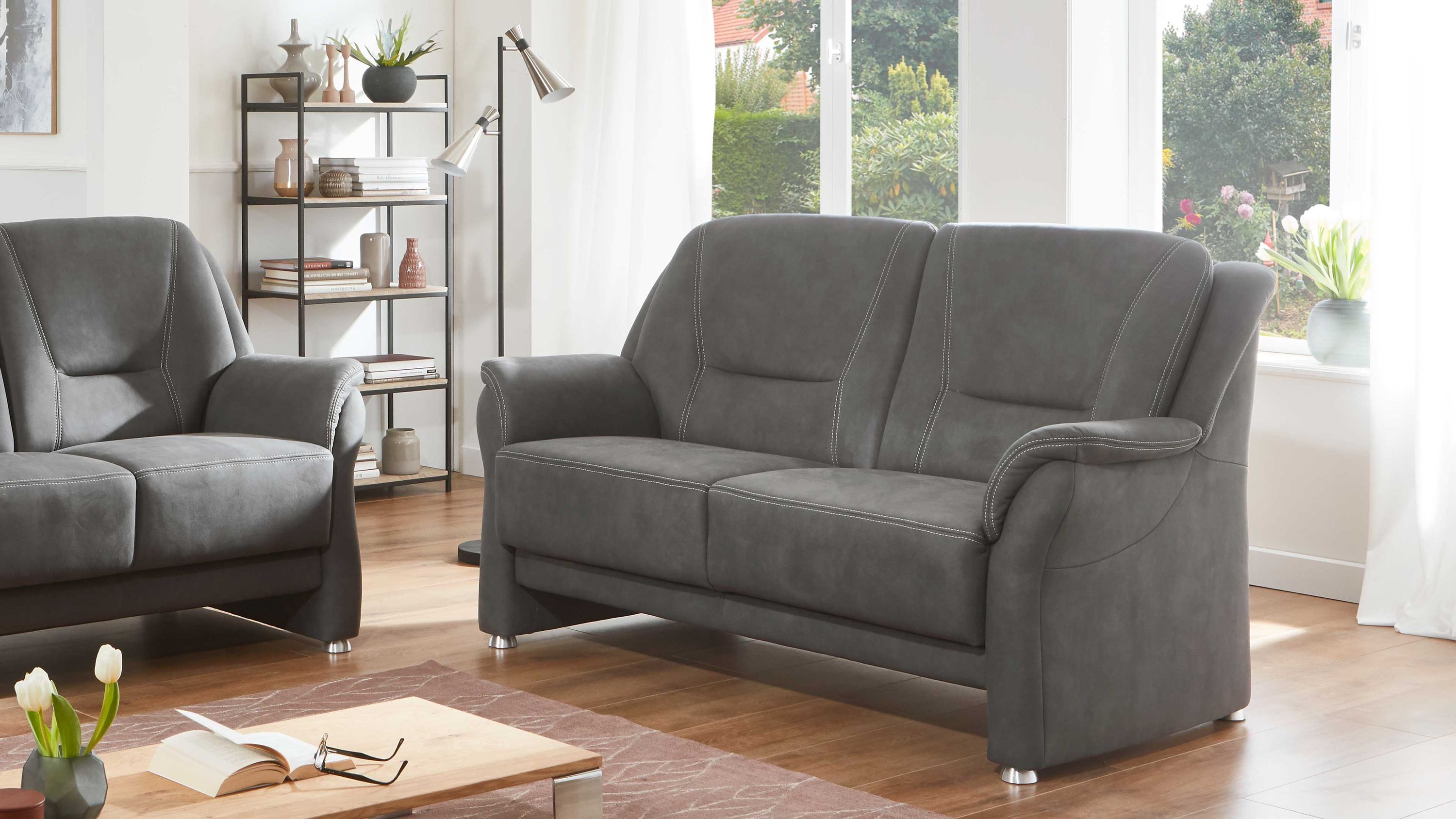 Zweisitziges Sofa mit grauem Mikrofaserbezug und Metallfüßen in hellem Wohnzimmer