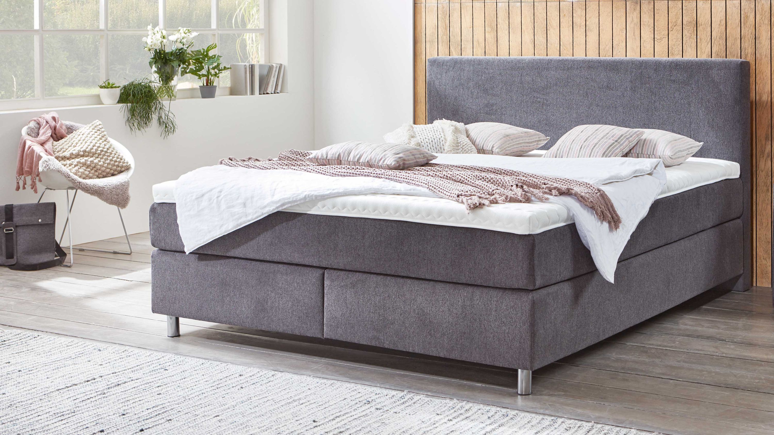 Boxspringbett mit rechteckigem Kopfteil und grauem Stoffbezug in modernem Schlafzimmer