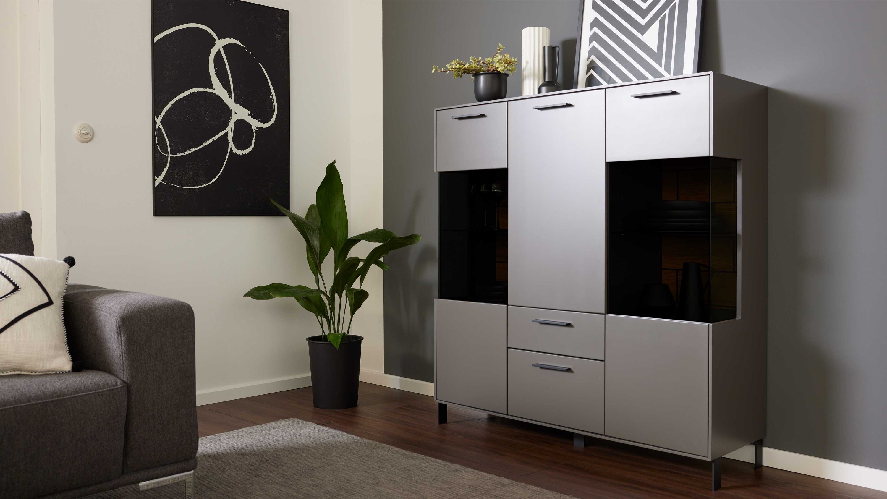 Hohes graues Sideboard mit Türen und Schubladen Hohes Sideboard mit drei Türen zwei Schubladen und schwarzen Glaseinsätzen in grauer Farbe
