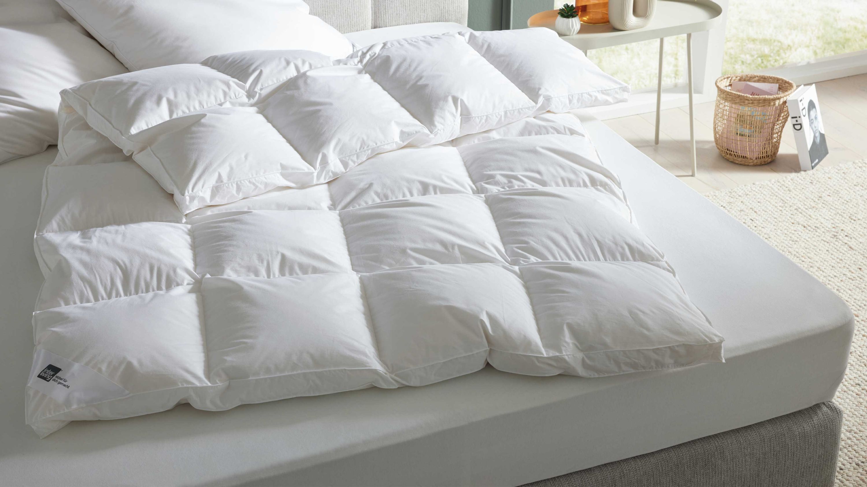 Weiße gesteppte Bettdecke mit quadratischen Kammern auf einem weißen Bett mit Kopfkissen