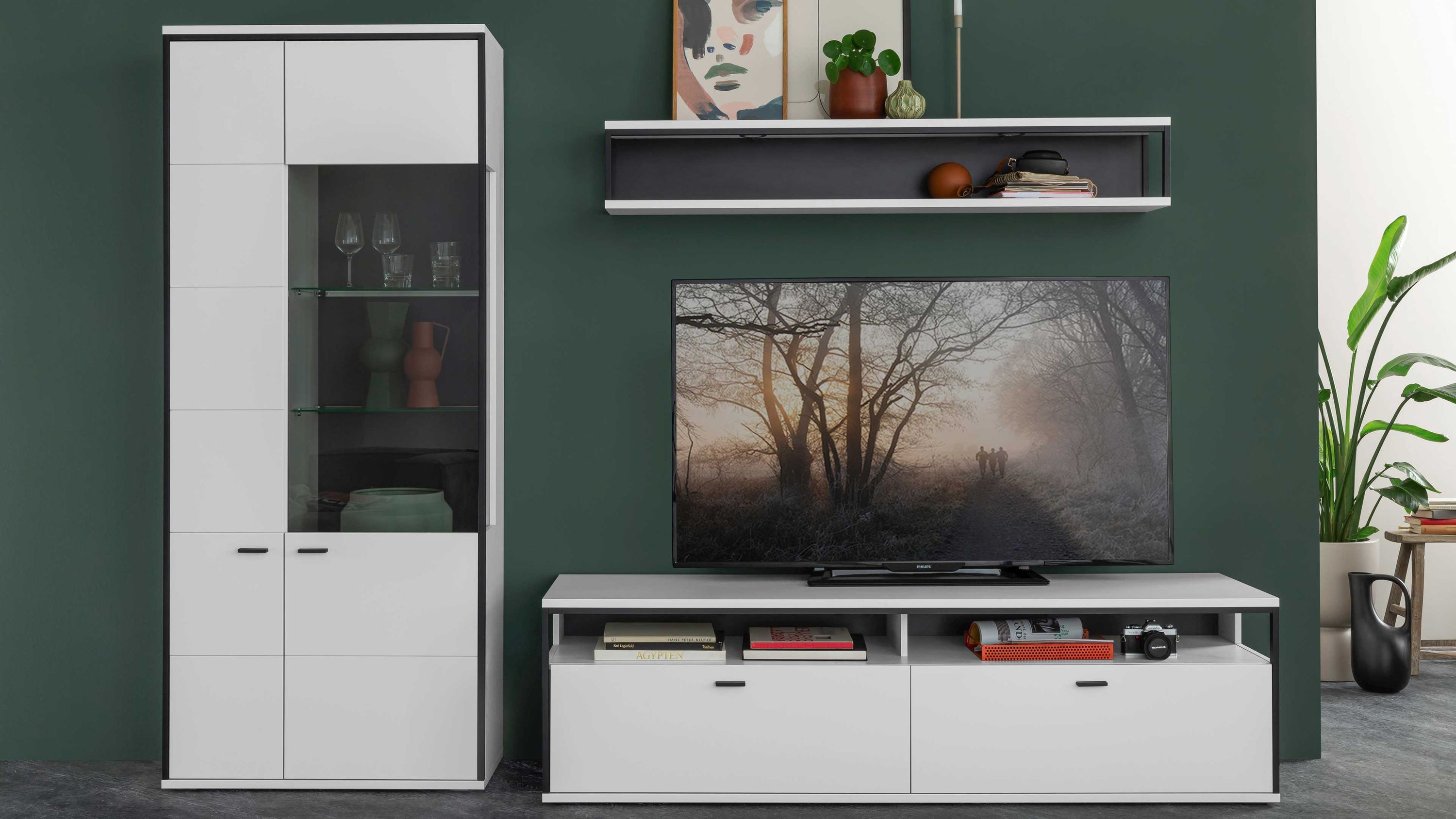 Dreiteilige Wohnwand in Weiß und Schwarzgrau Dreiteilige Wohnwand mit weiß lackierten Fronten und schwarzgrauen Kanten bestehend aus Vitrine TV-Board und Wandregal