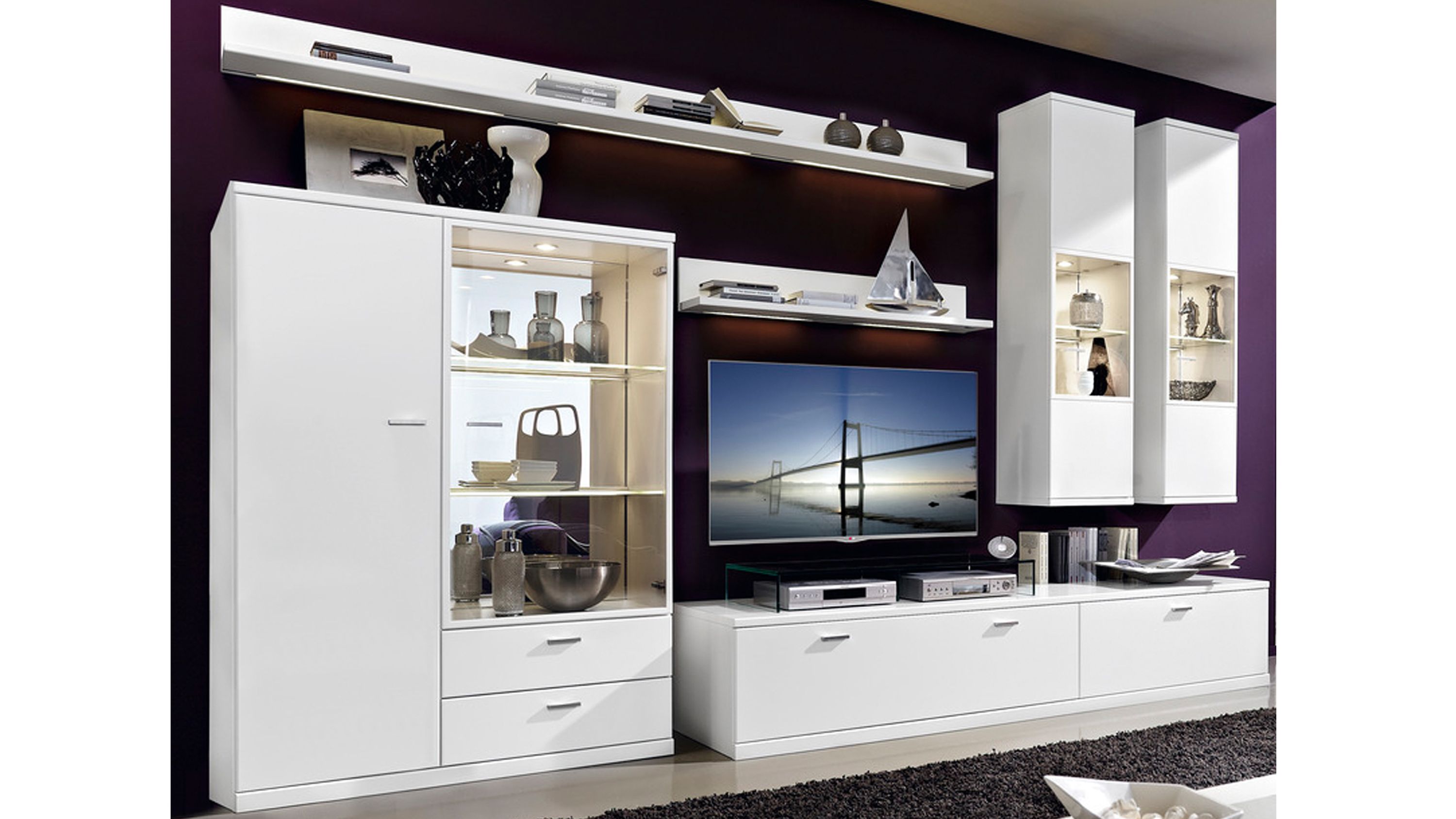 Weiße Wohnkombination mit Vitrinenschrank und TV-Board Weiße Wohnkombination mit Vitrinenschrank Hängeschränken Regalen und TV-Board mit mattweißen Oberflächen