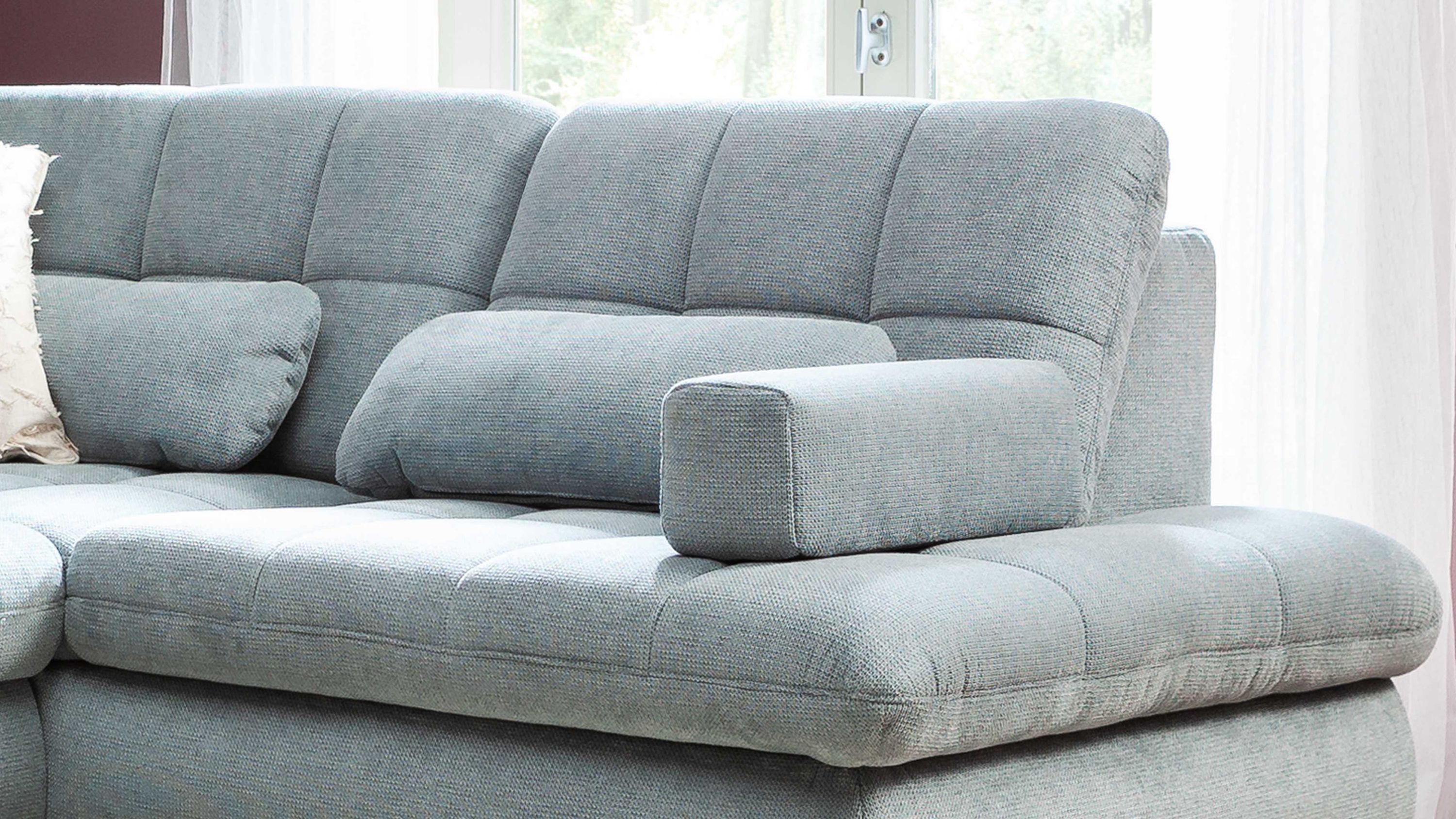 Rechteckiges Armlehnkissen in stahlblau auf einem hellblauen Sofa mit gepolstertem Stoffbezug