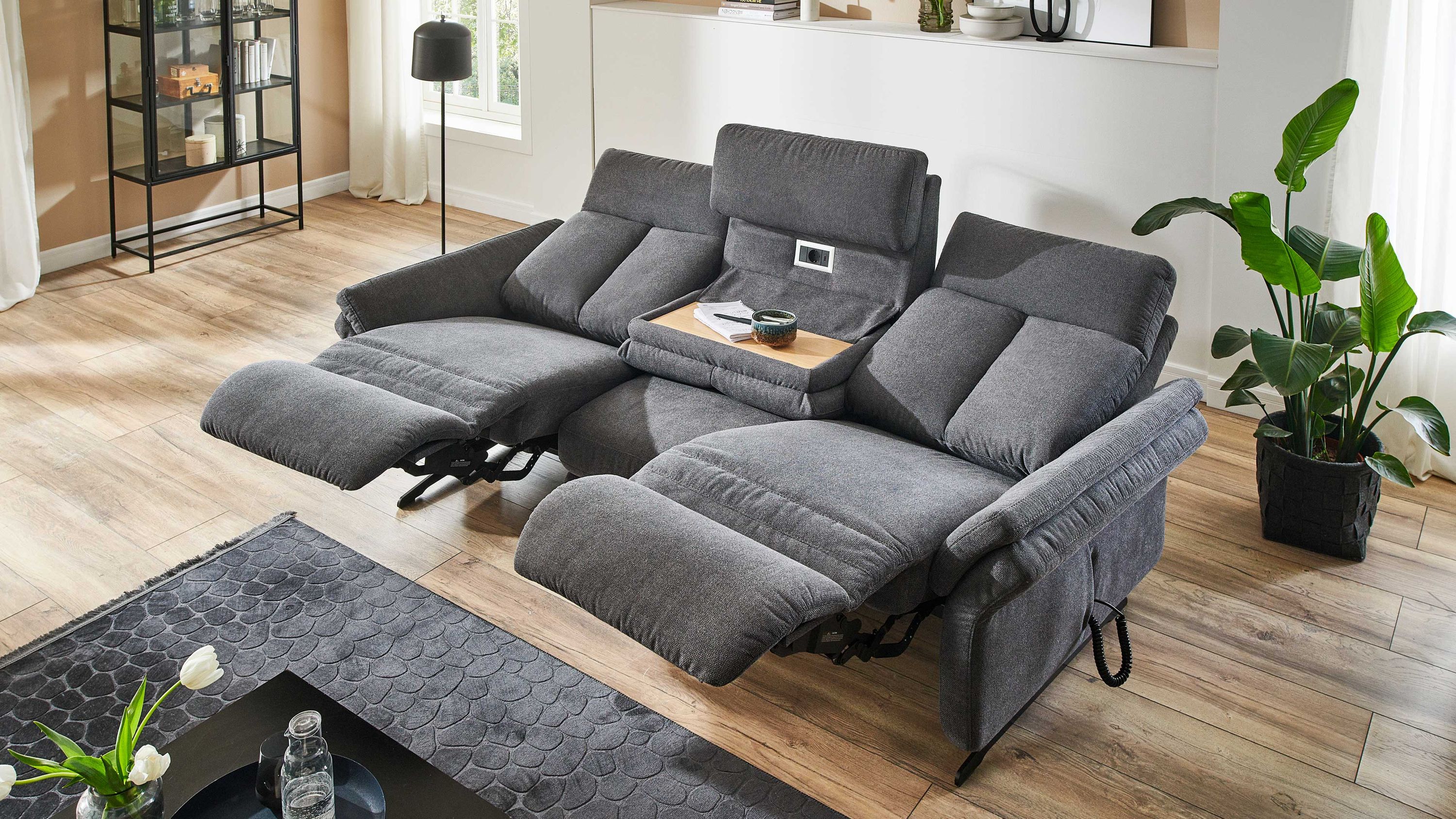 Rundsofa mit Funktionen in Anthrazit Anthrazitfarbenes Rundsofa mit zwei ausklappbaren Fußstützen und integriertem Tisch