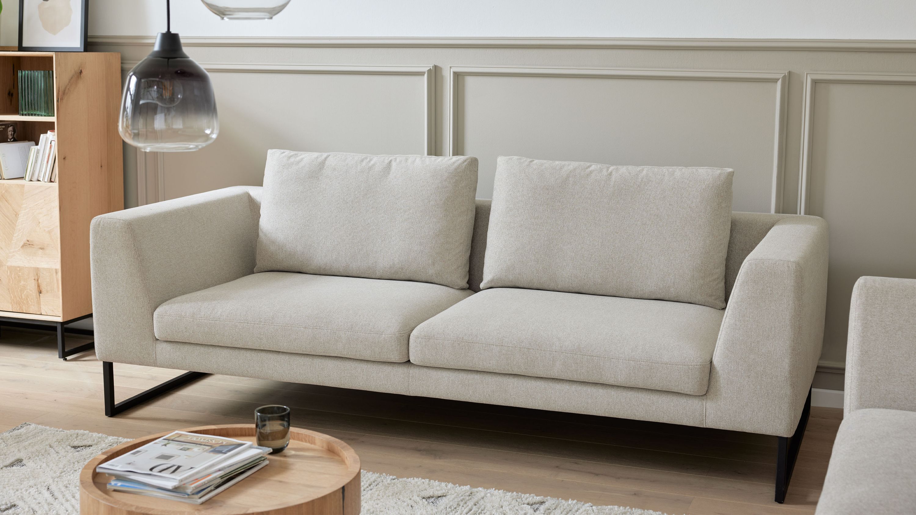 Dreisitzersofa mit sandfarbenem Bezug und schwarzen Kufenfüßen Dreisitziges Sofa mit sandfarbenem Bezug und schwarzen Kufenfüßen in modernem Wohnzimmer