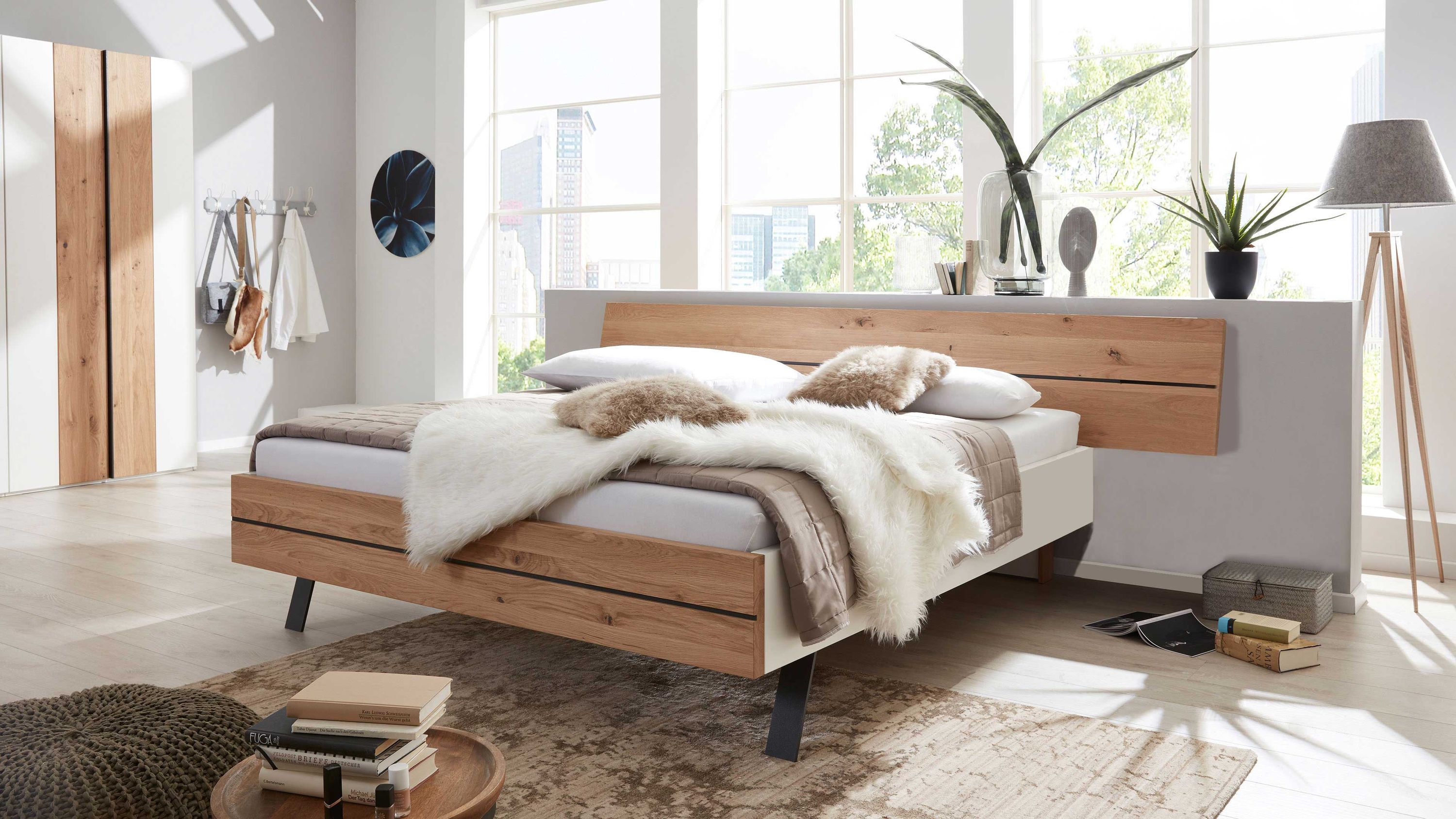 Bettgestell mit rechteckigem Kopfteil und Fußteil aus Holz in heller Farbe und weißem Rahmen in modernem Schlafzimmer