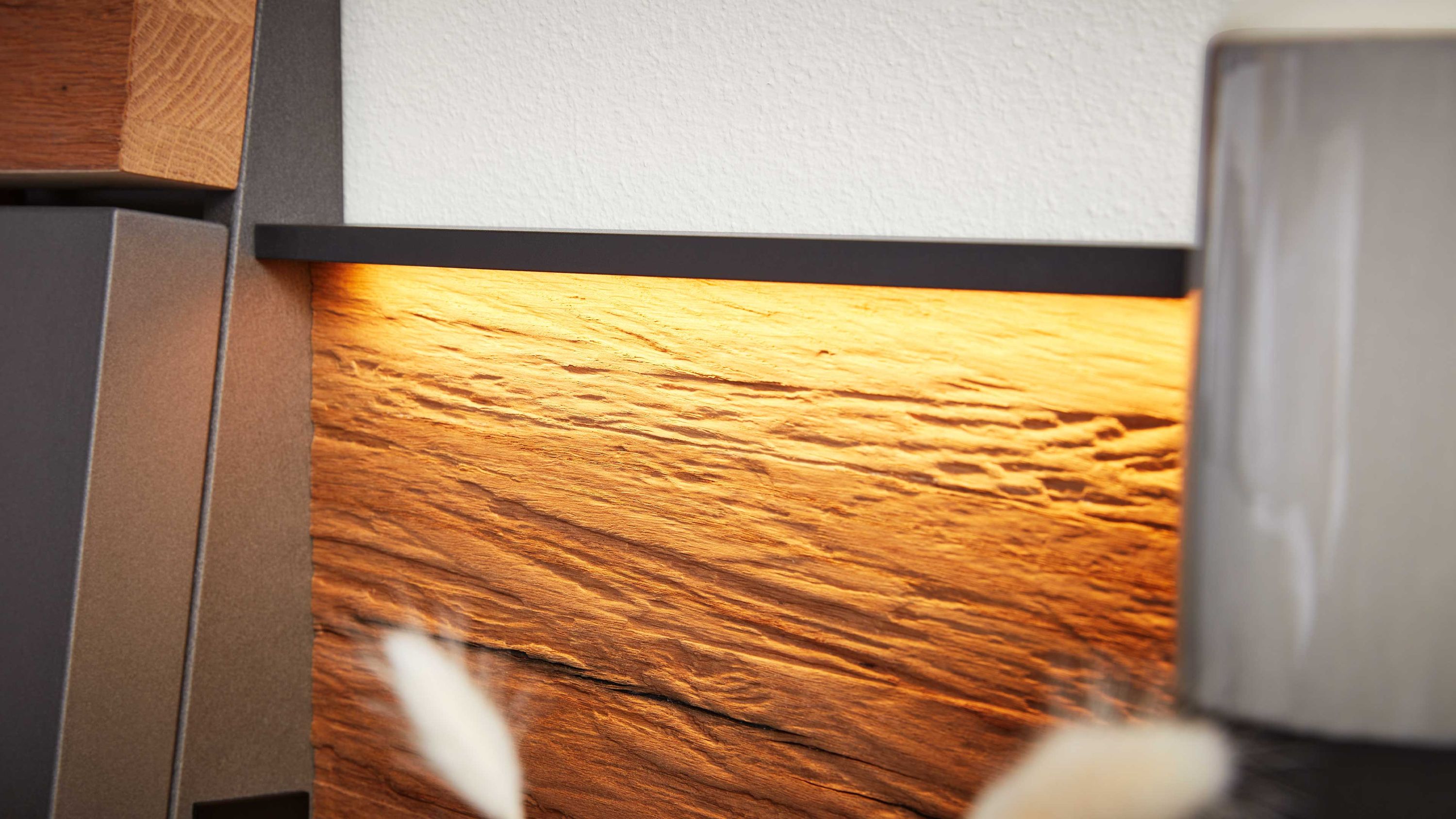 Beleuchtetes Holzpaneel mit sichtbarer Maserung und schwarzem Rahmen an der Wand