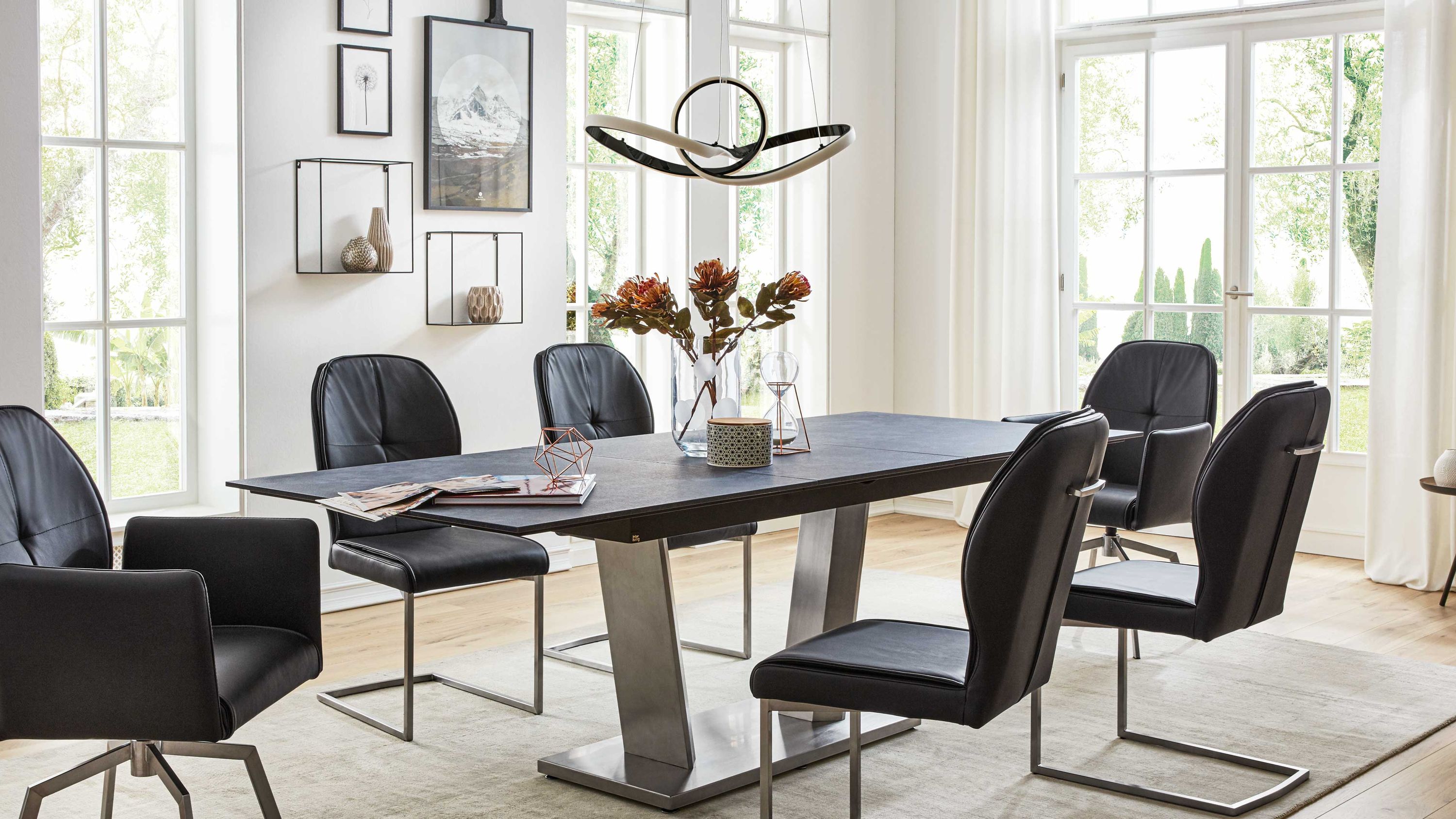 Auszugtisch mit terrafarbener Platte und Edelstahlgestell Auszugtisch mit rechteckiger terrafarbener Tischplatte und Edelstahlgestell in hellem Esszimmer mit schwarzen Stühlen