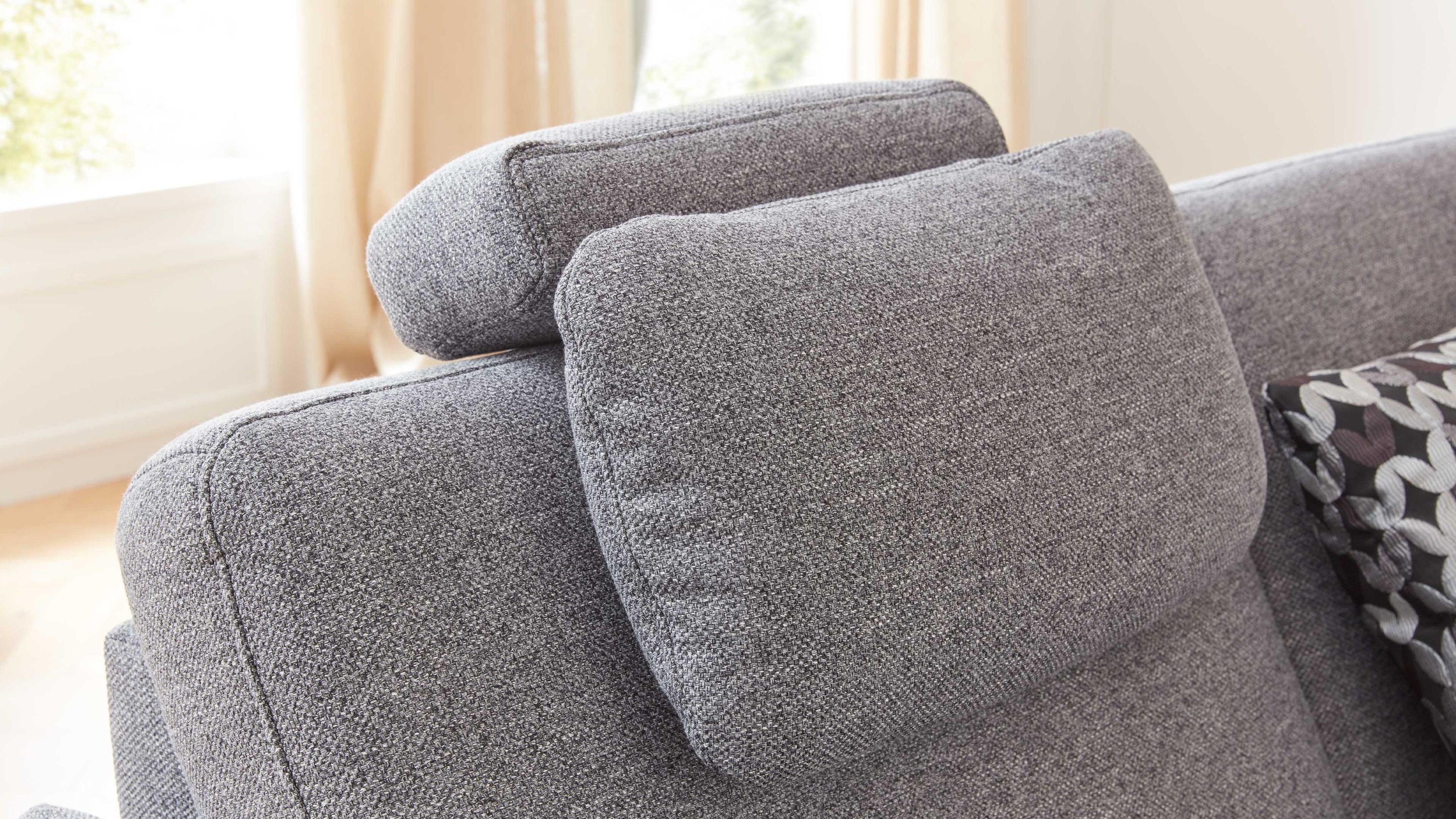 Kopfstütze aus grauem Flachgewebe auf Sofa Graue Kopfstütze aus Flachgewebe auf grauem Sofarücken