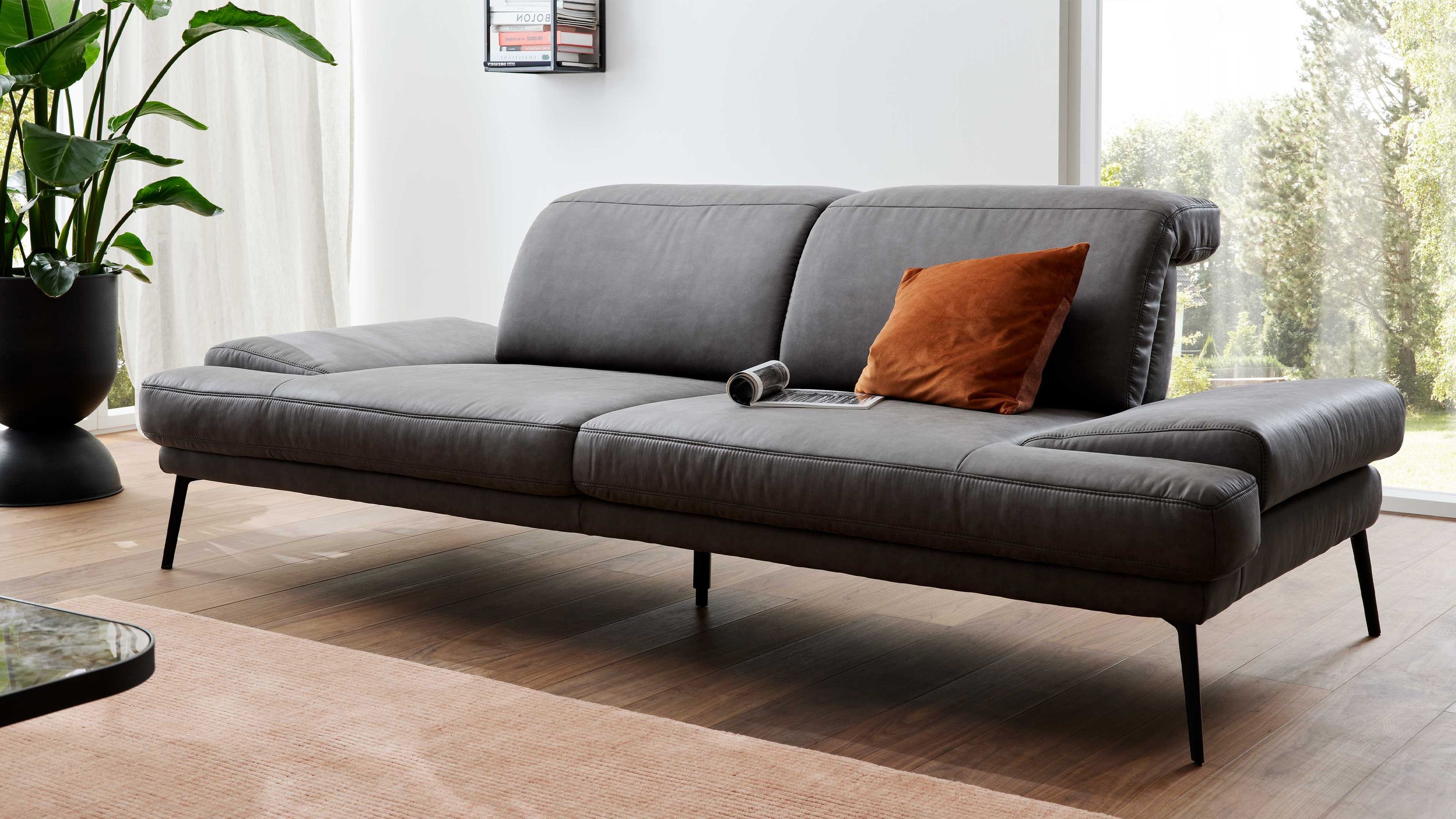 Graues Sofa mit zwei Sitzplätzen schwarzen Metallfüßen und einem braunen Kissen