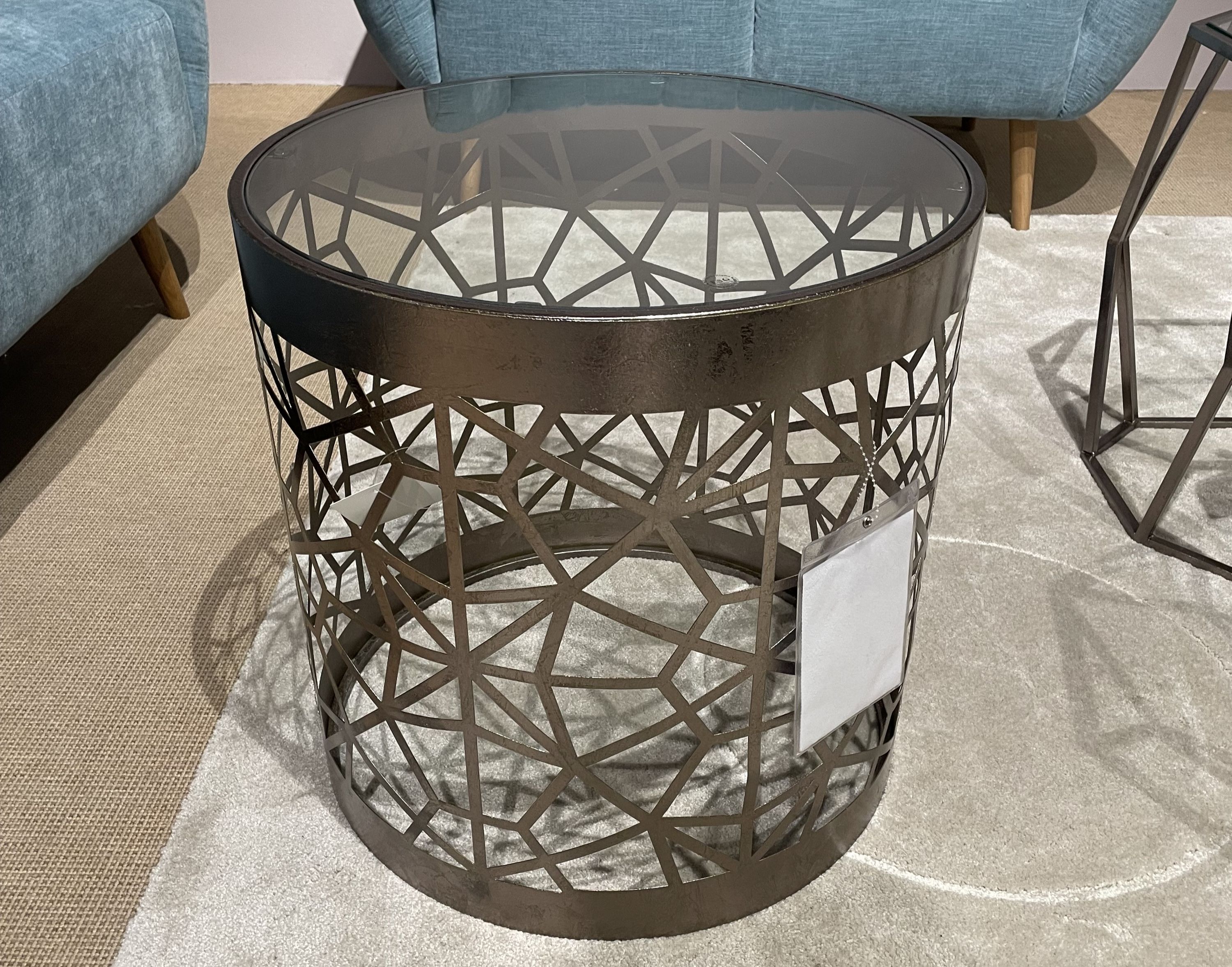 Runder Beistelltisch mit bronzefarbenem Metallgestell in geometrischem Muster und Glasplatte.