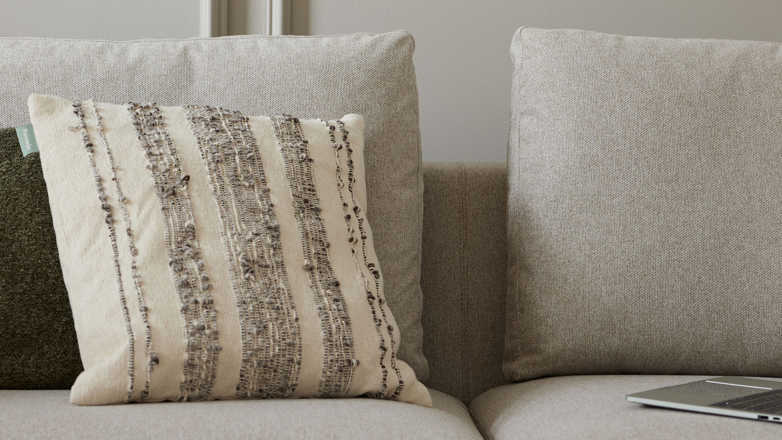 Kissenhülle mit Streifenmuster auf Sofa Quadratische Kissenhülle mit beigen und schwarzen Streifen auf einem hellgrauen Sofa