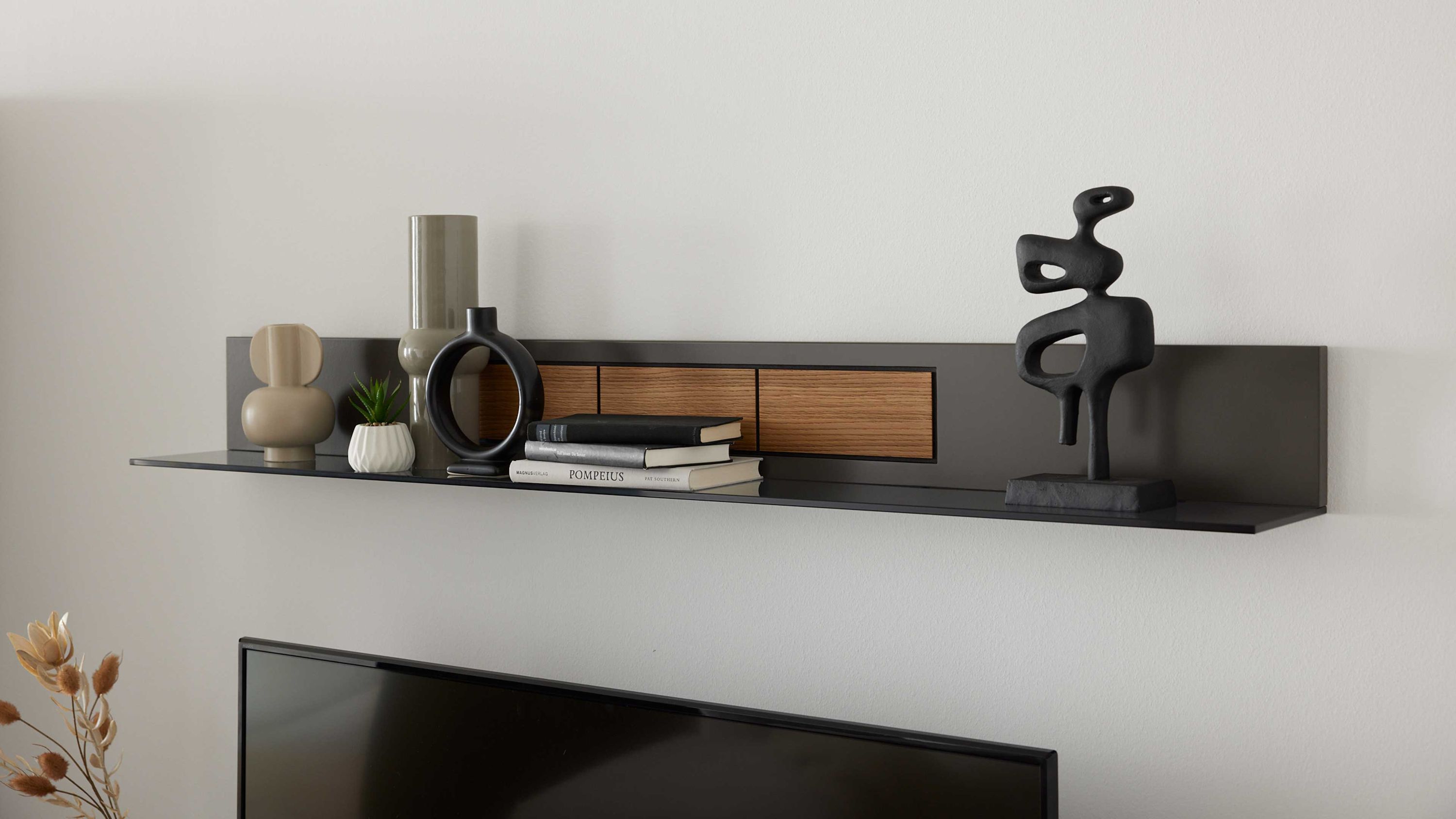 Schwarzes Wandregal mit Holzdetails dekoriert mit Vasen Büchern und einer abstrakten Skulptur