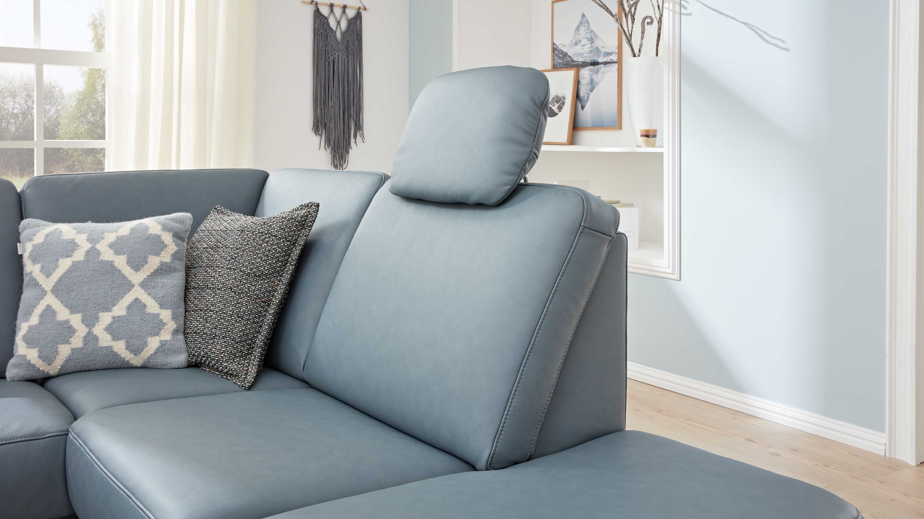 Ecksofa mit stahlblauem Bezug und verstellbarer Kopfstütze zwei Kissen in Grau und Weiß