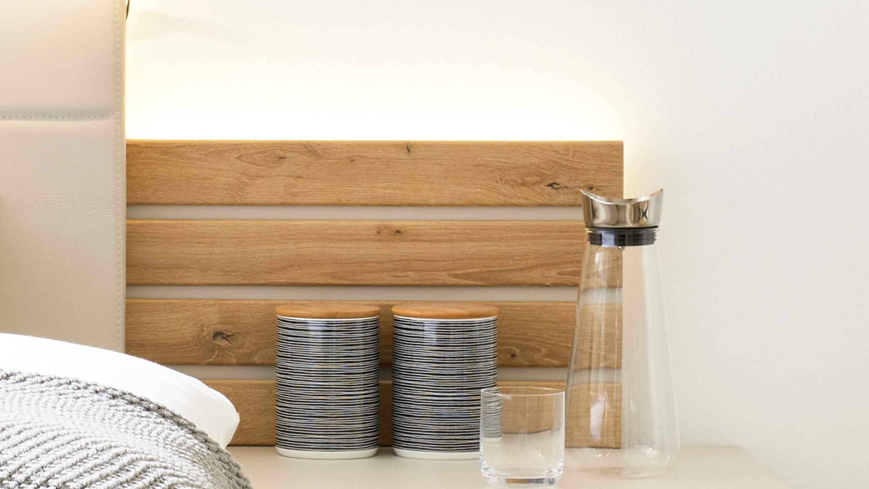 Zweiteiliges Paneelbeleuchtungs-Set mit Holzpaneel in hellbraun und zwei gestreiften Behältern sowie Glasflasche und Glas