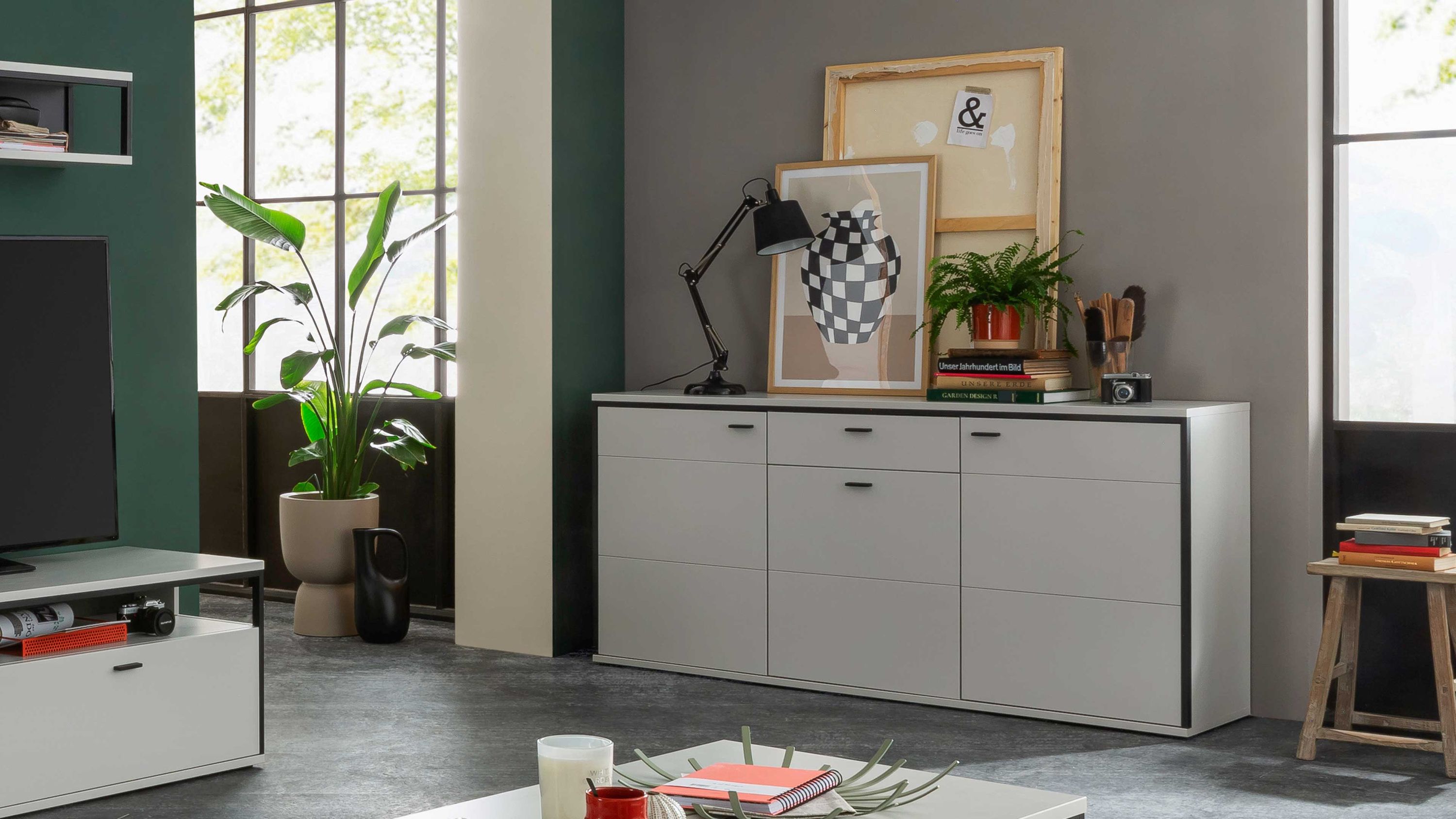 Weißes Sideboard mit schwarzen Kanten und Schublade Sideboard mit drei Türen und einer Schublade in Weiß mit schwarzer Kante in modernem Wohnzimmer
