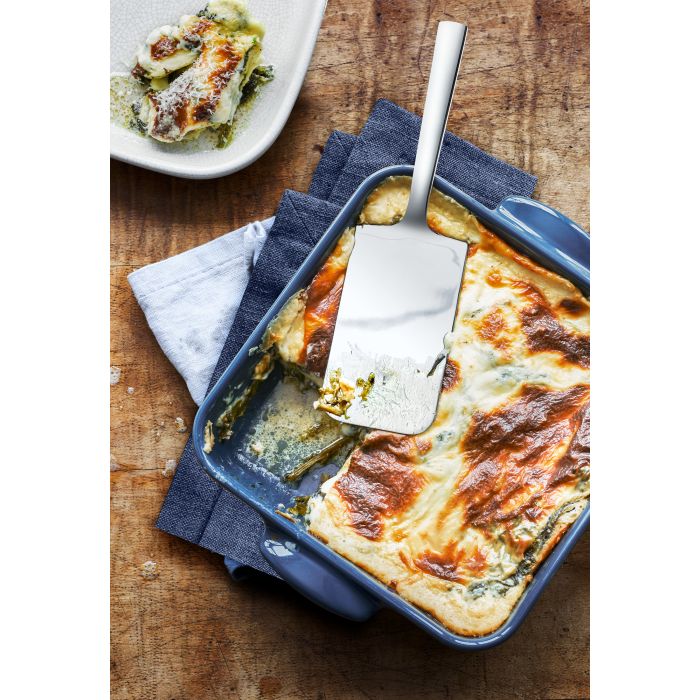 Edelstahl-Lasagneheber in blauer Auflaufform mit überbackener Lasagne auf Holzuntergrund von oben fotografiert